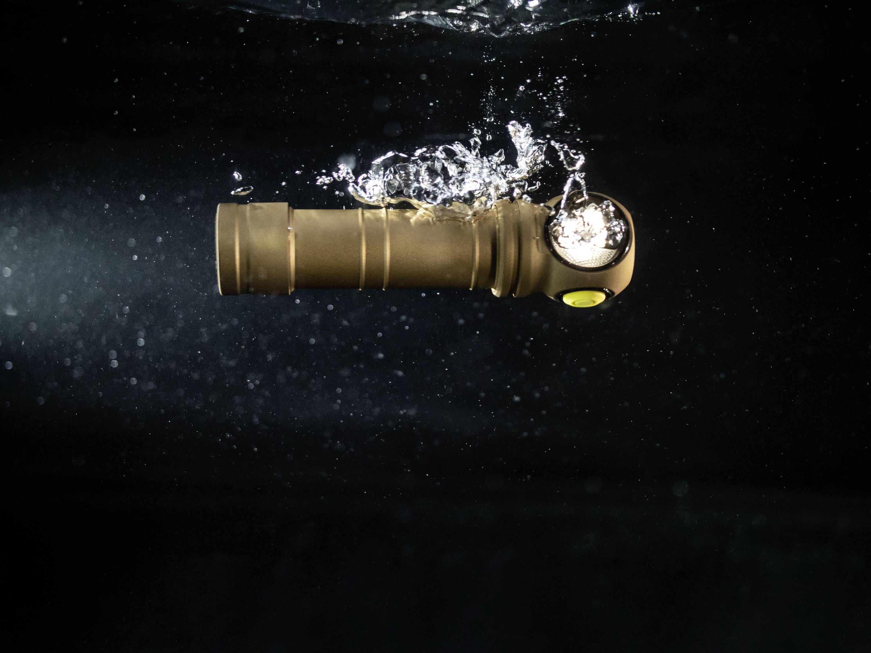 Zaklamp onder water met het licht aan, luchtbellen stijgen op. Hij toont duurzaamheid en waterdichtheid.