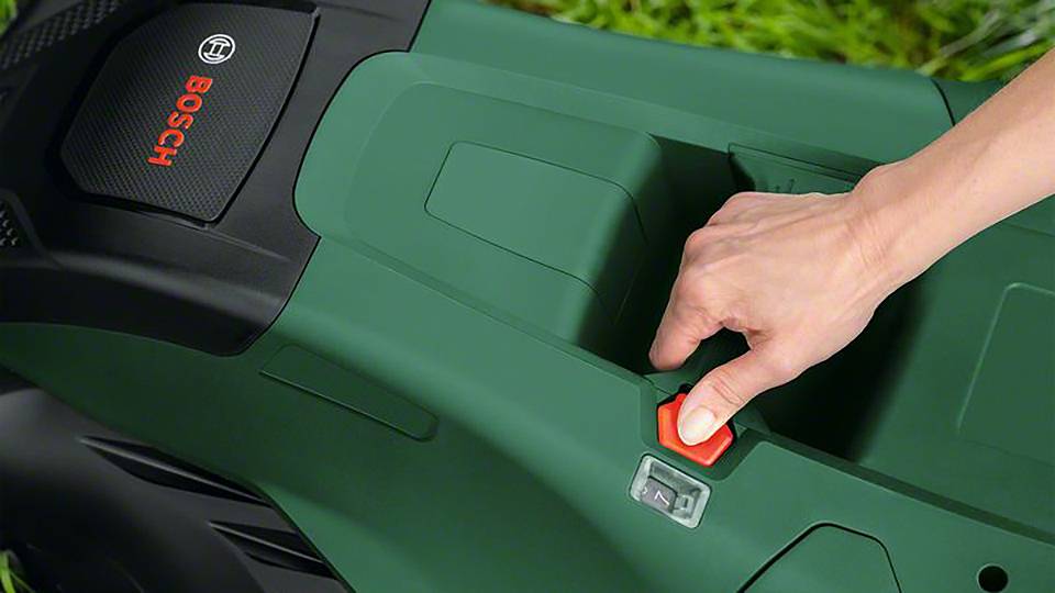 Een persoon drukt op de startknop van een groene grasmaaier met het Bosch-logo.