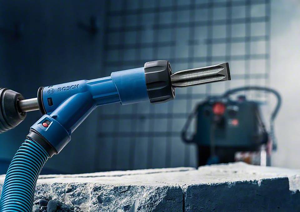 Boor op de bouwplaats in close-up; een stofzuiger op de achtergrond.