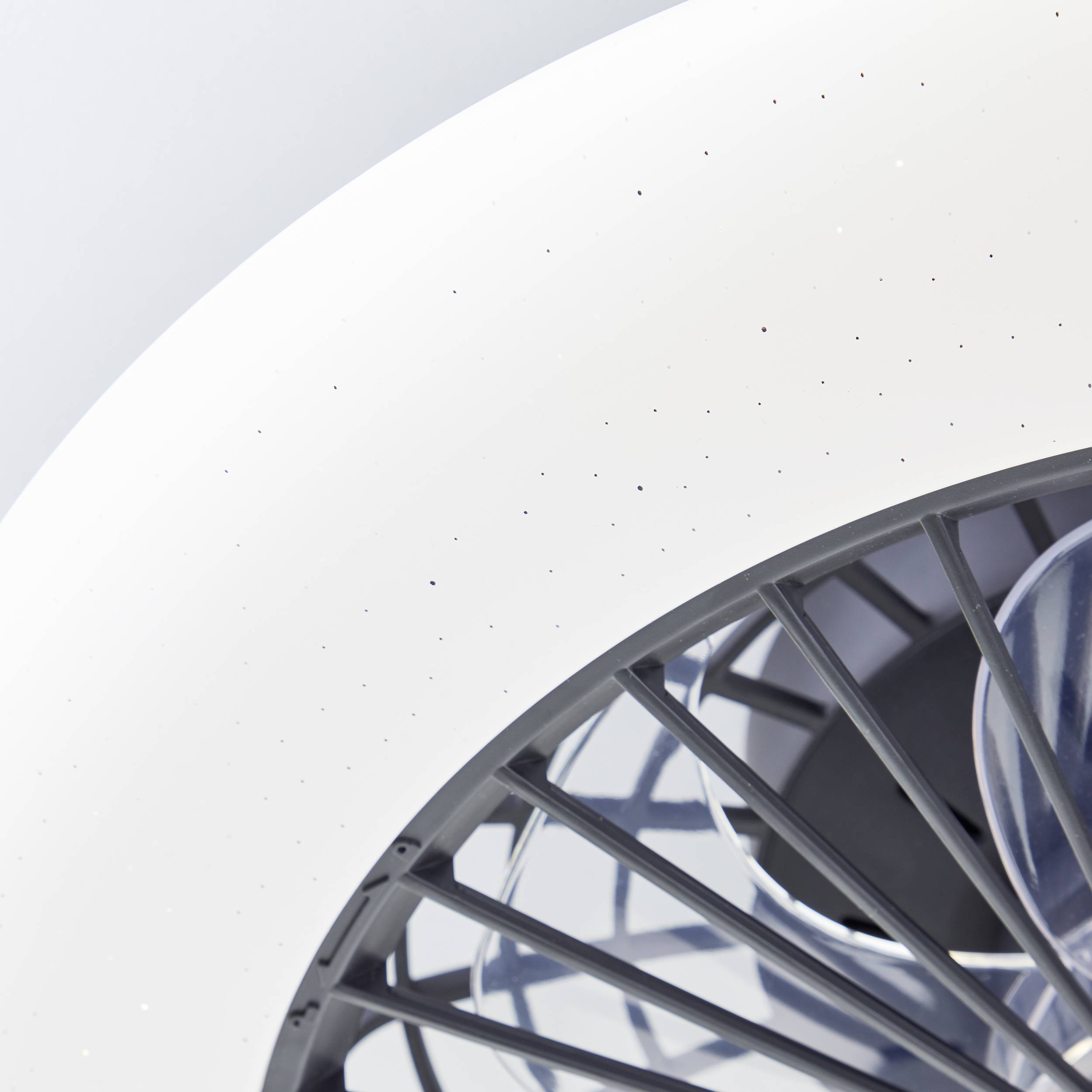 Een witte, ronde ventilator gefotografeerd van bovenaf, waarbij zijn draaiende grijze schoepen zichtbaar zijn.