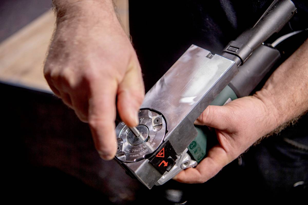 Close-up van handen die een regelaar op een elektrisch apparaat instellen. De wijzerplaat toont verschillende instellingen.