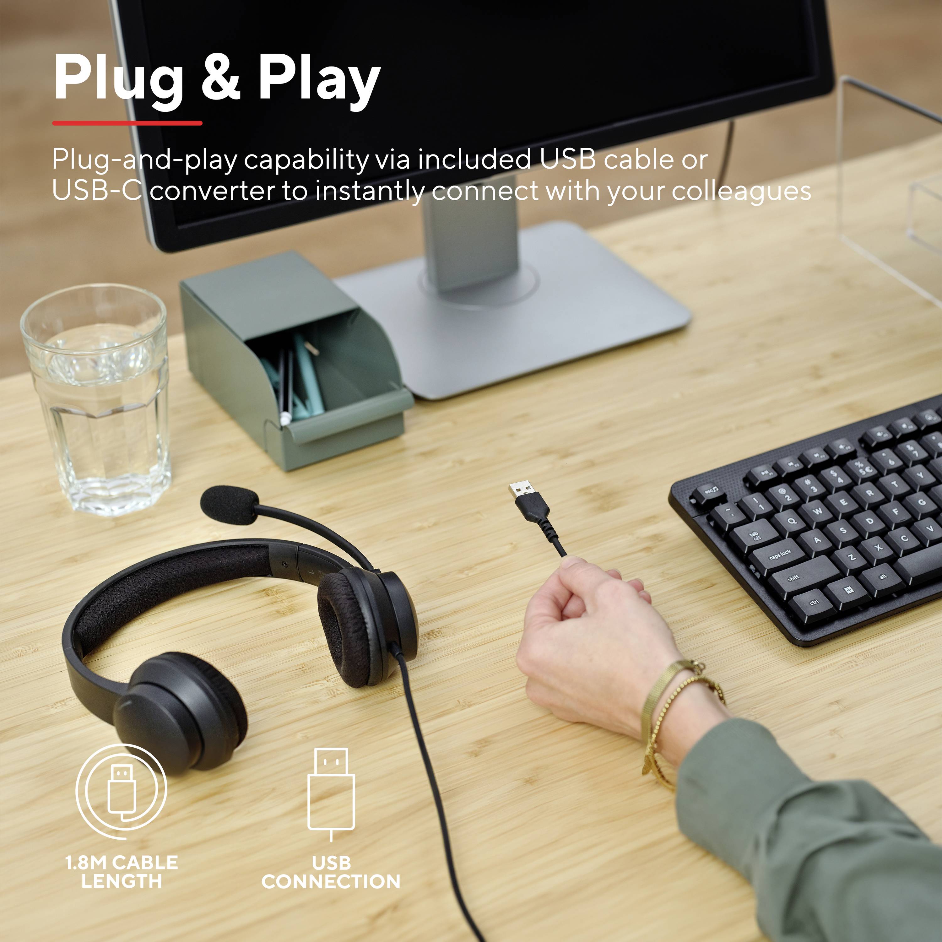 Werkplek met computer, toetsenbord, koptelefoon en USB-kabel. Persoon houdt kabel vast om deze aan te sluiten. Tekst: 'Plug & Play.'