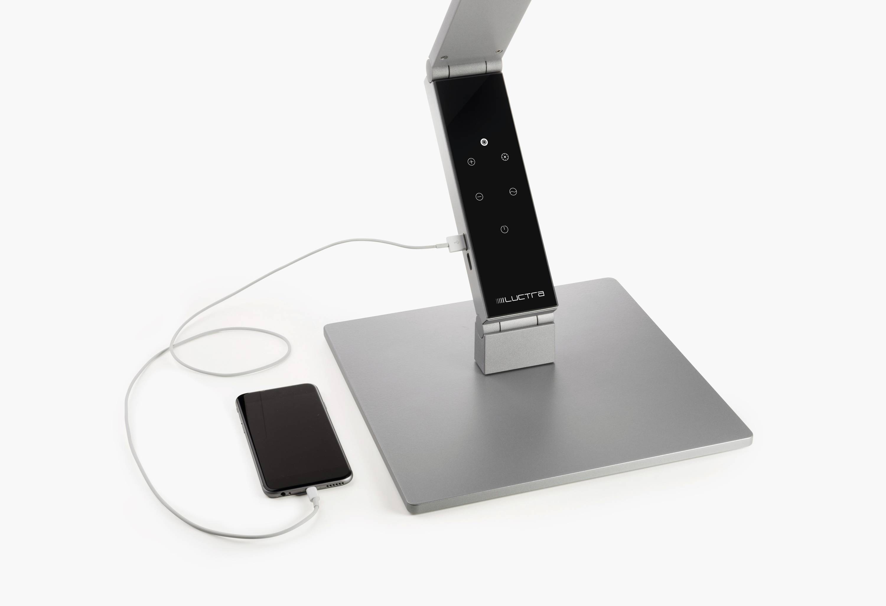 Een moderne tafellamp met touch-bediening en een smartphone die via een oplaadkabel met de lamp is verbonden.