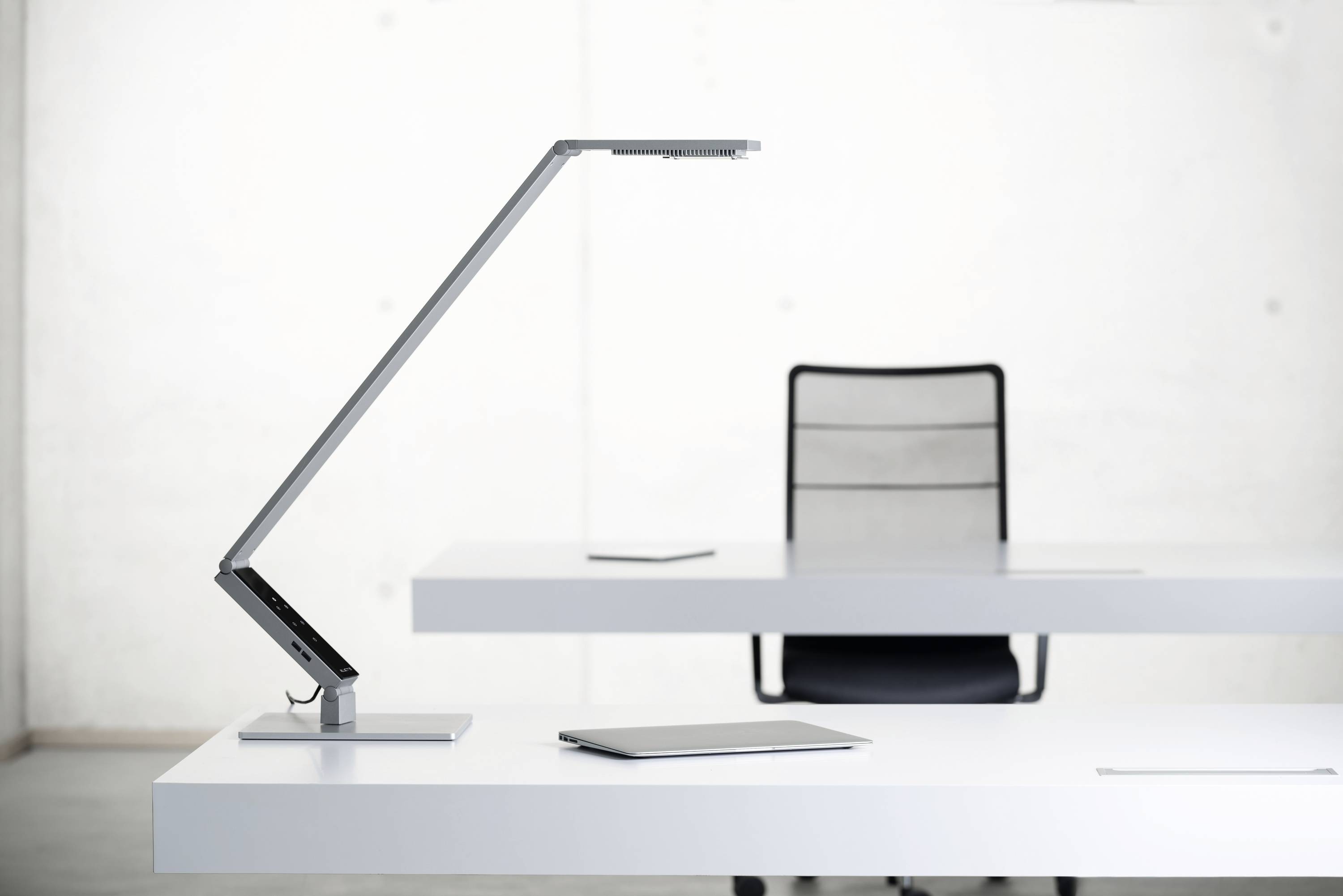 'Een moderne, minimalistische bureau met een slanke LED-bureaulamp en een tablet in een lichte kantoorruimte.'
