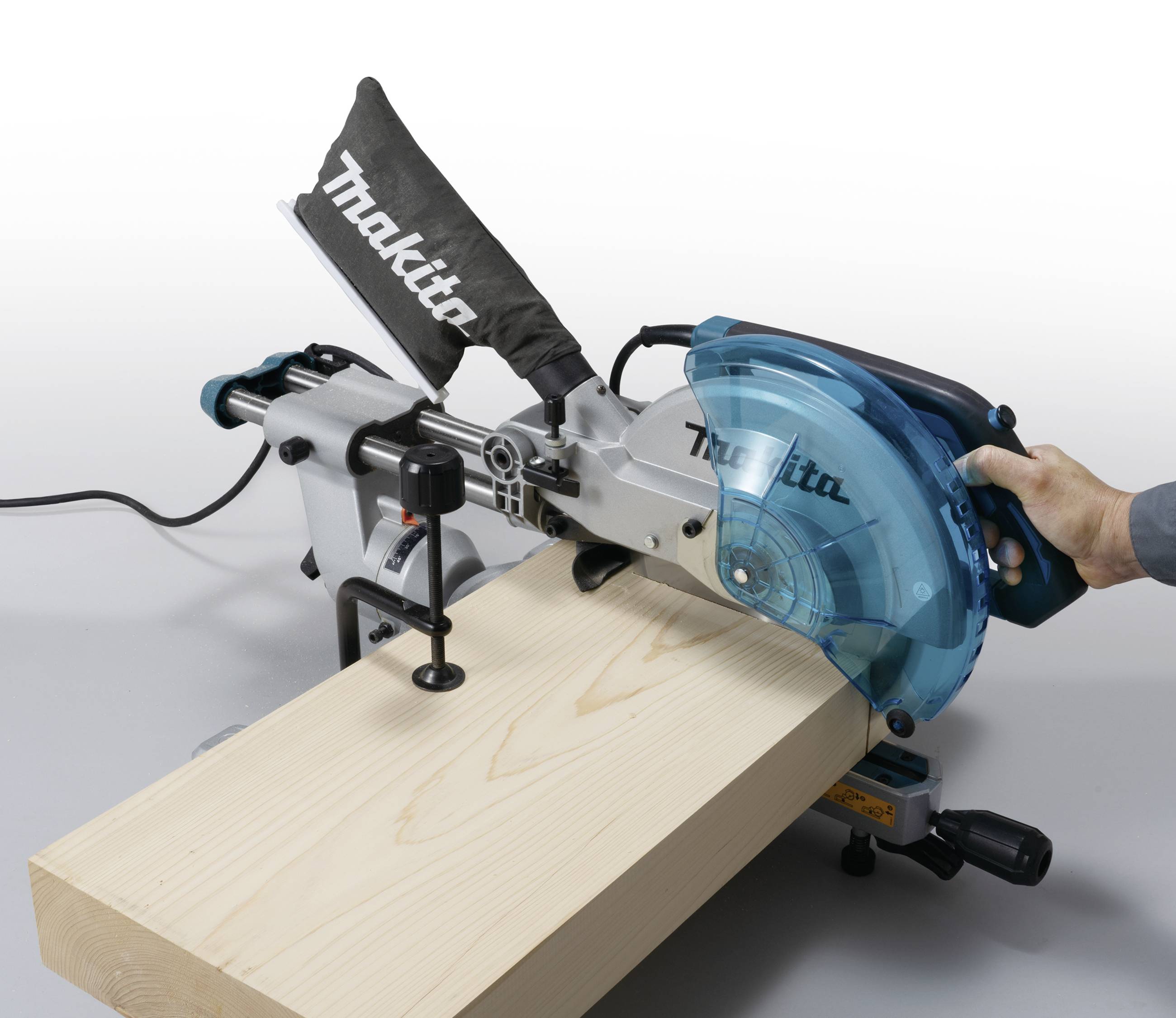 Een verstekzaag zaagt een houten plank. Een hand houdt het handvat van de zaag vast, terwijl de plank op de zaagbank ligt.