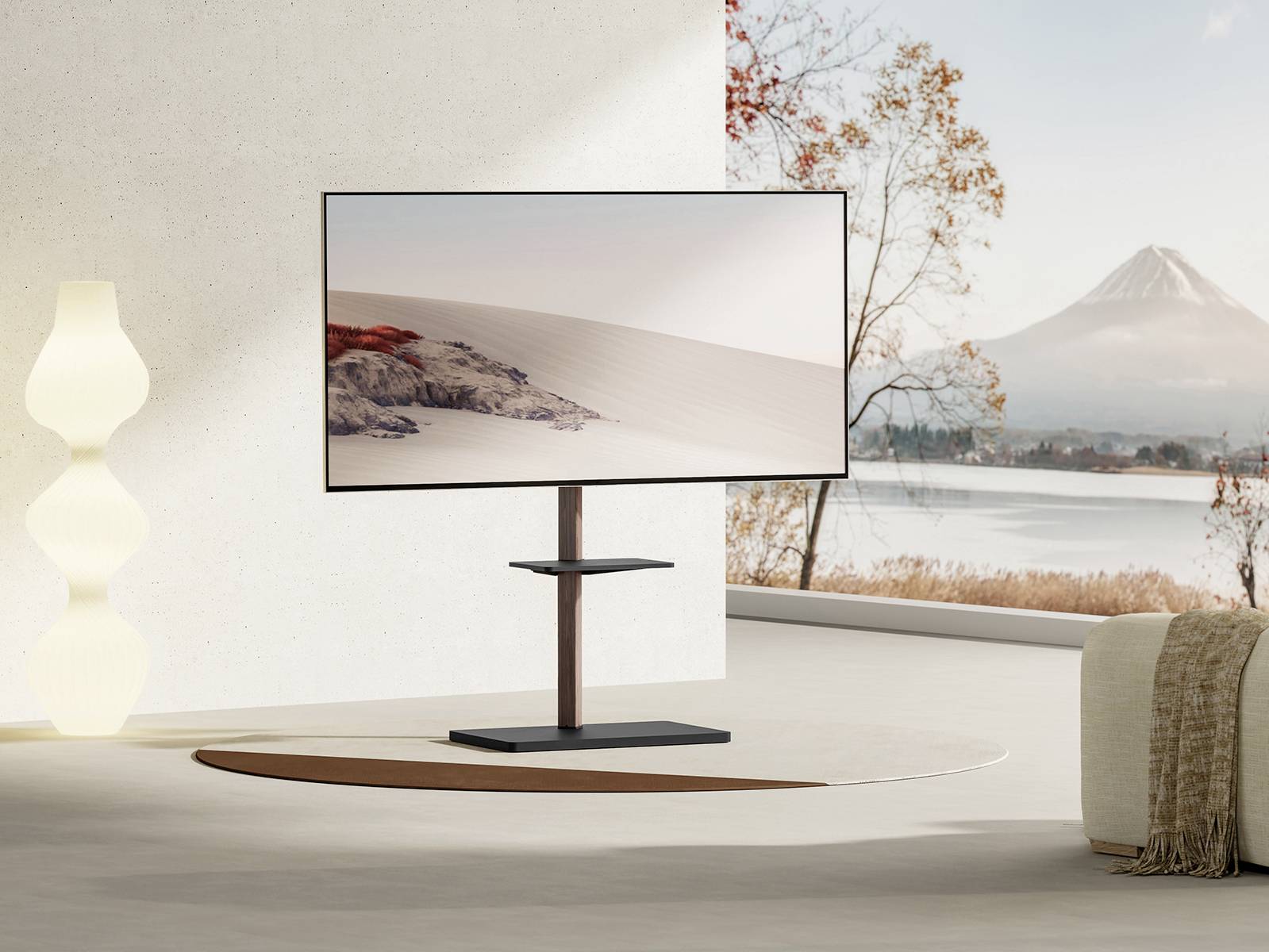 Moderne televisie op een standaard in een stijlvolle woonkamer met een groot raam dat een landschap met bergen en een meer toont.