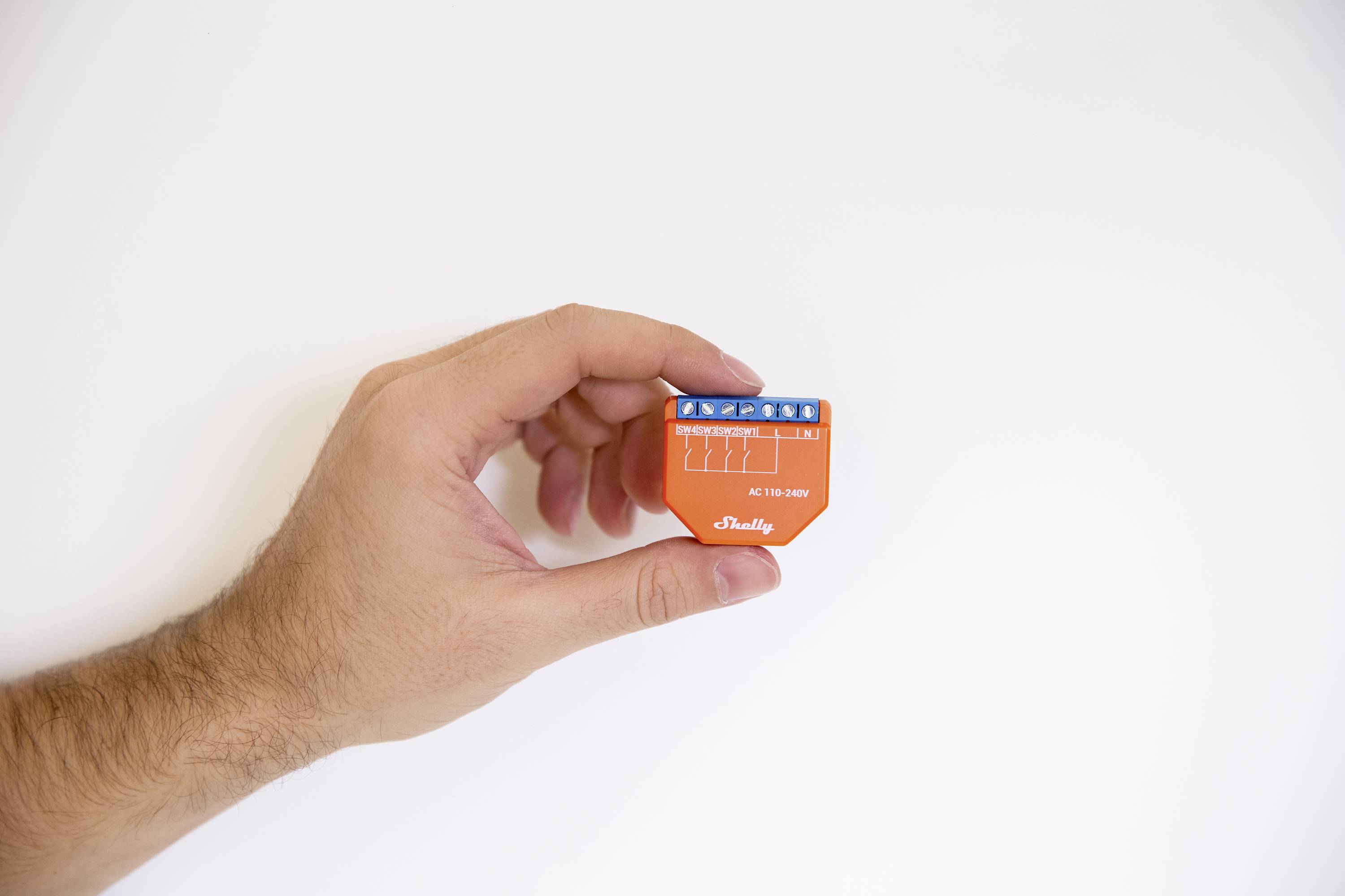 Een hand houdt een oranje elektronisch apparaat met een blauwe aansluitleiste vast.