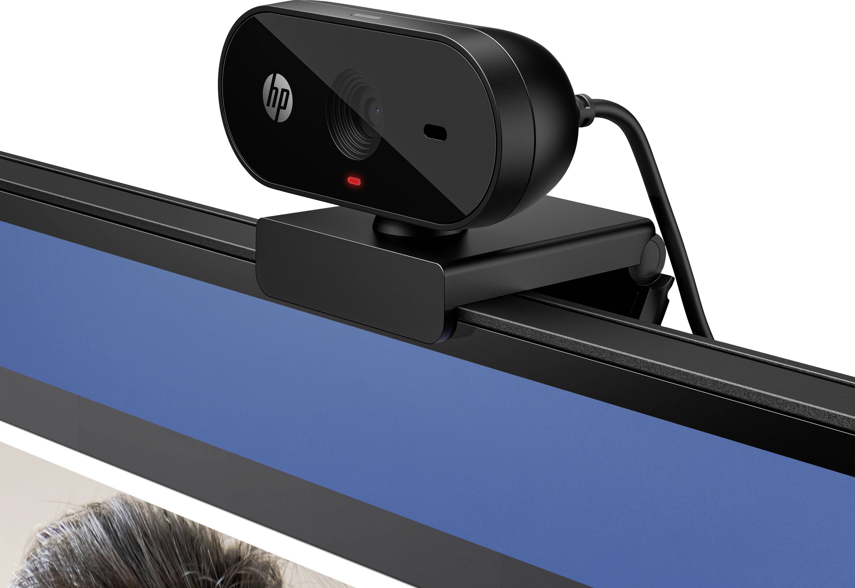 'Zwarte webcam gemonteerd op een monitor, toont een scherm met een blauwe achtergrond en een deel van een foto eronder.'