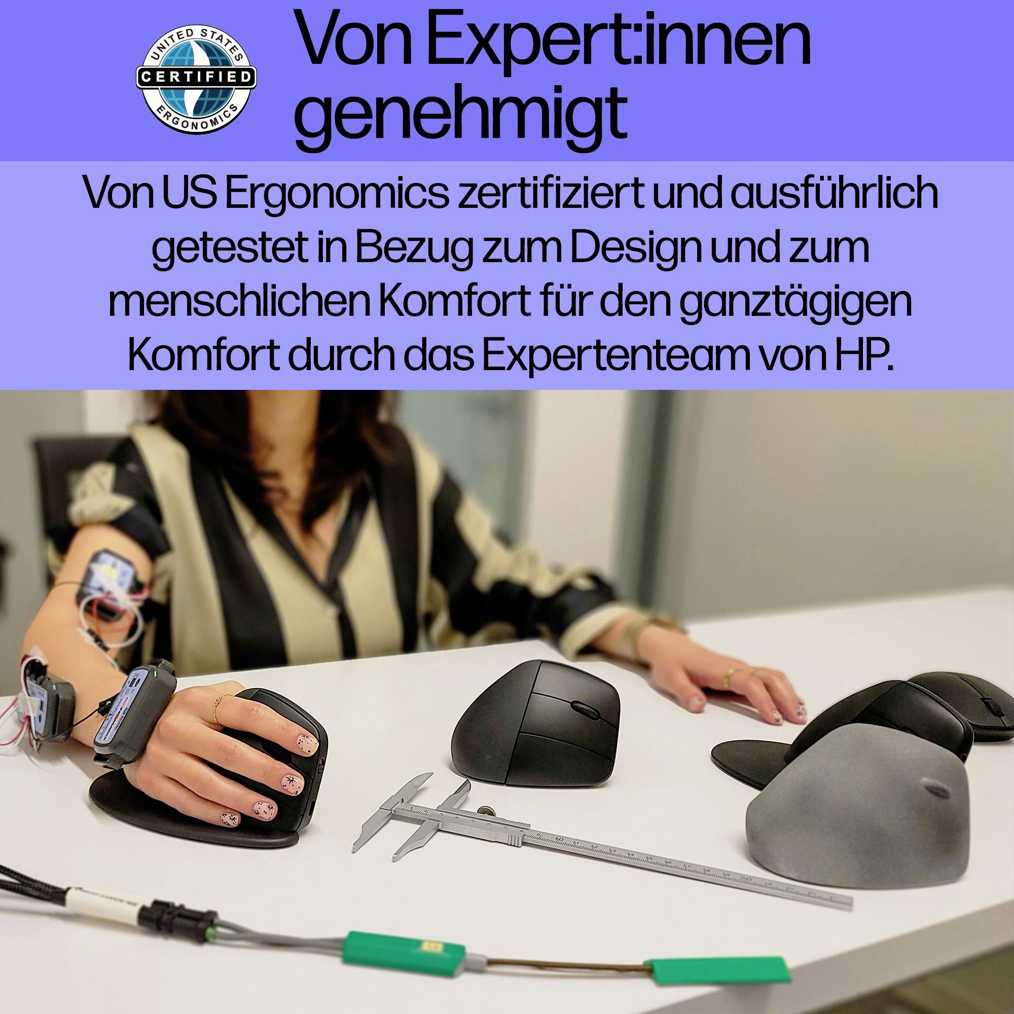 Een ergonomische computermuis gebruikt door een persoon op een tafel met meetinstrumenten, gecertificeerd door US Ergonomics.