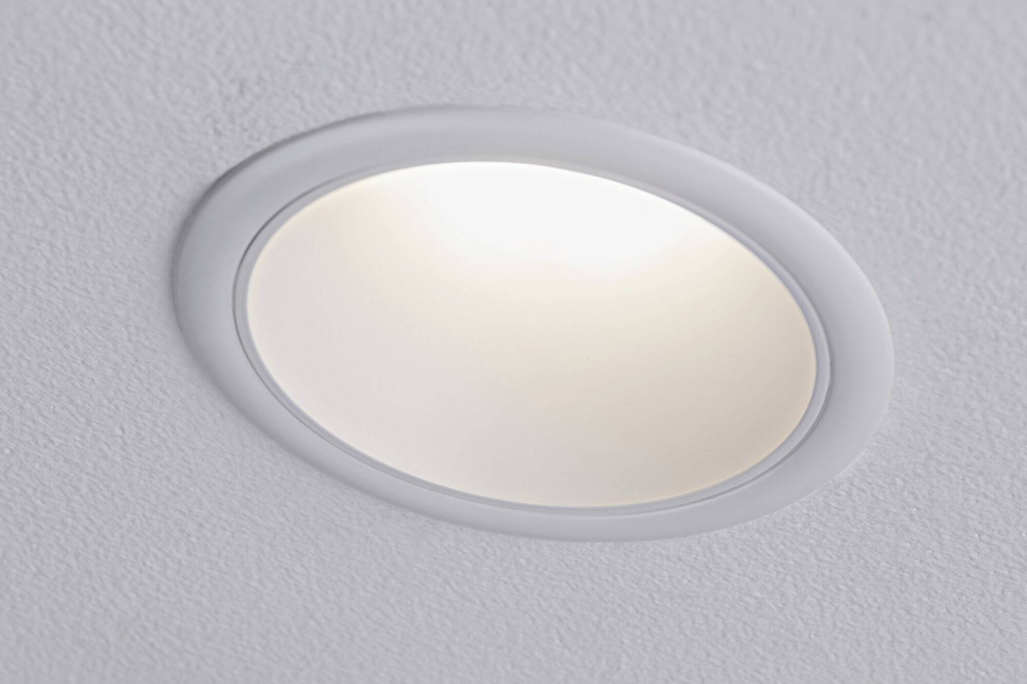 Een aan het plafond gemonteerde, ingebouwde ronde lamp die wit licht uitstraalt, ingebed in een gestructureerd wit plafondoppervlak.