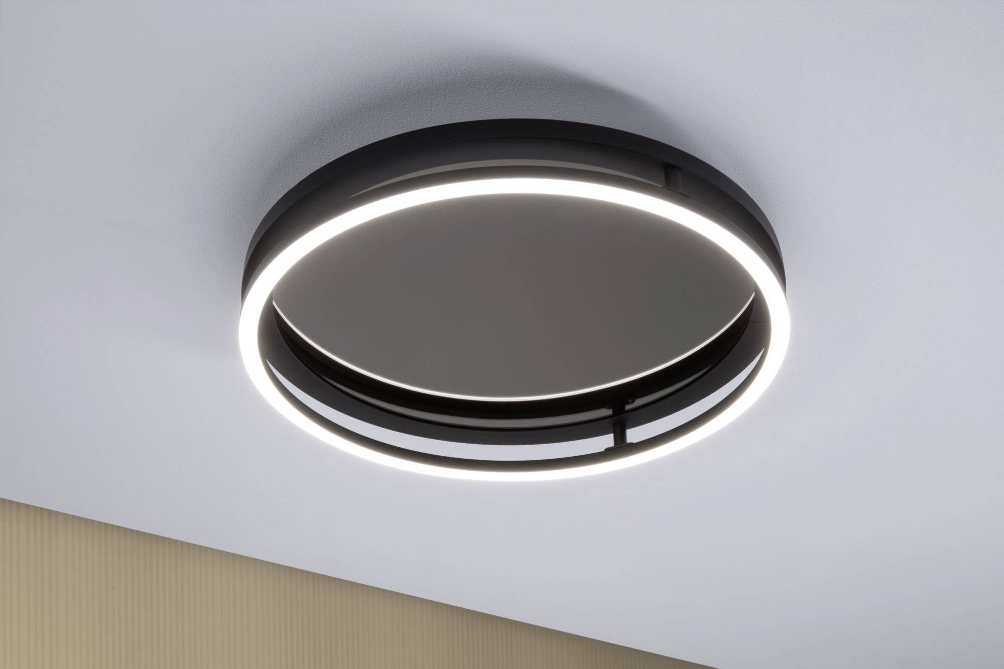 Ronde plafondlamp met modern design en LED-lichtring, gemonteerd aan een witte plafond, geeft gelijkmatig licht in de ruimte.