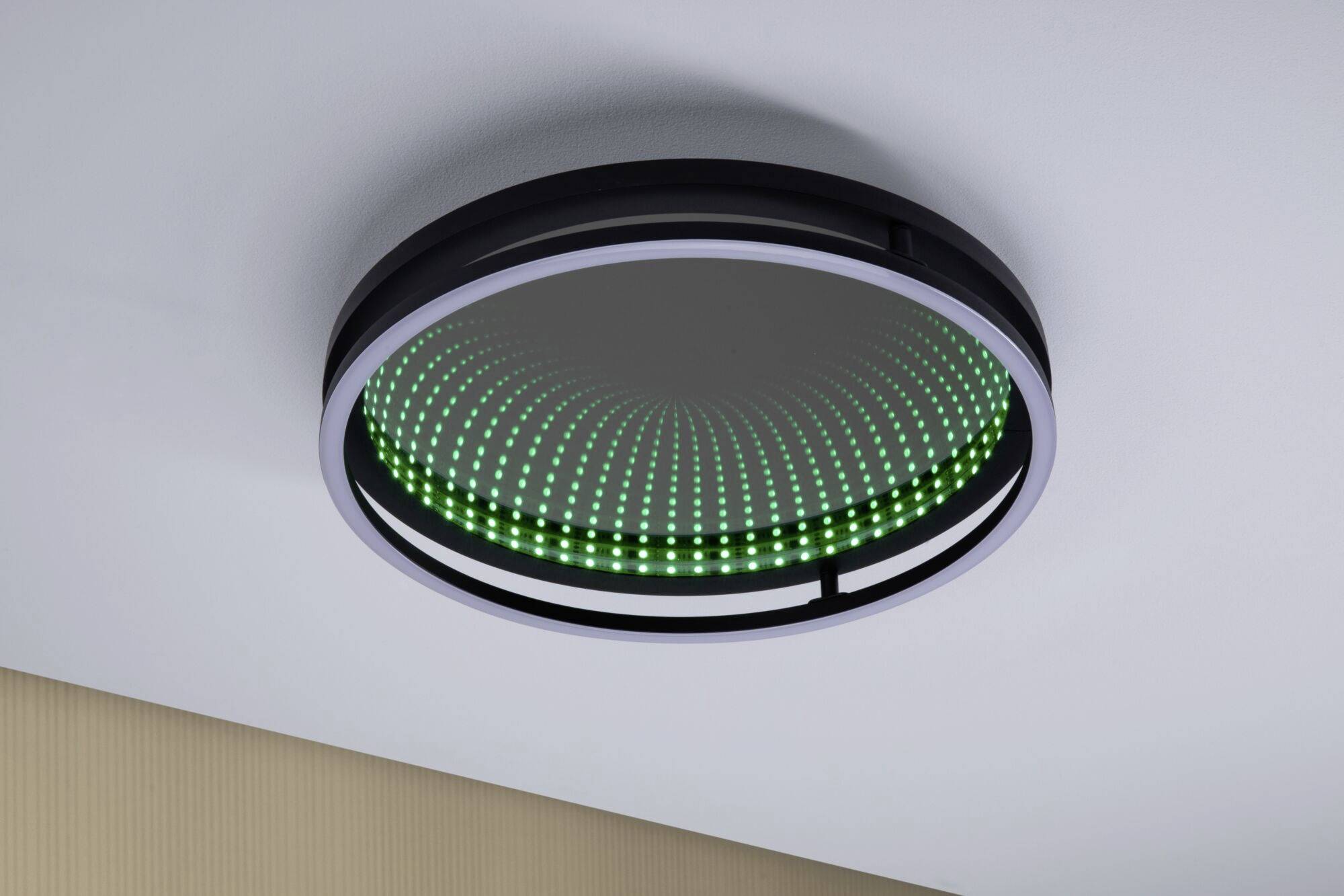 Een ronde plafondlamp met een patroon van lichtgevende groene LED's op een spiegelachtergrond, creëert een 3D-effect.