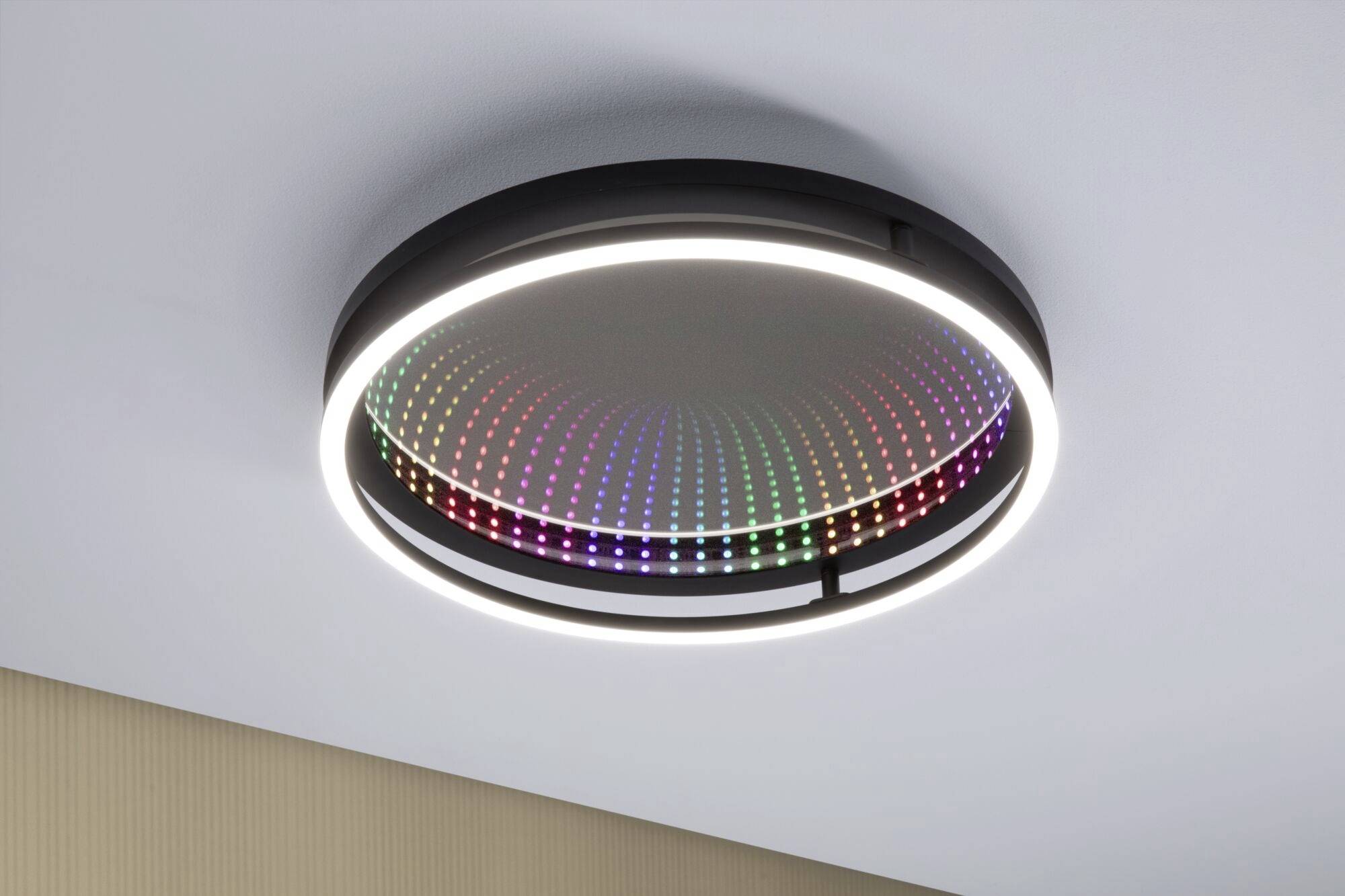 Ronde plafondlamp met LED-verlichtingsring, zwevend aan het plafond. Van binnen toont hij een patroon van kleurrijke, veranderende lichten.