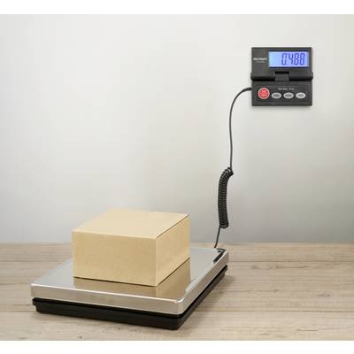 Een kartonnen doos staat op een digitale weegschaal die een gewicht van 7,488 kg aangeeft.