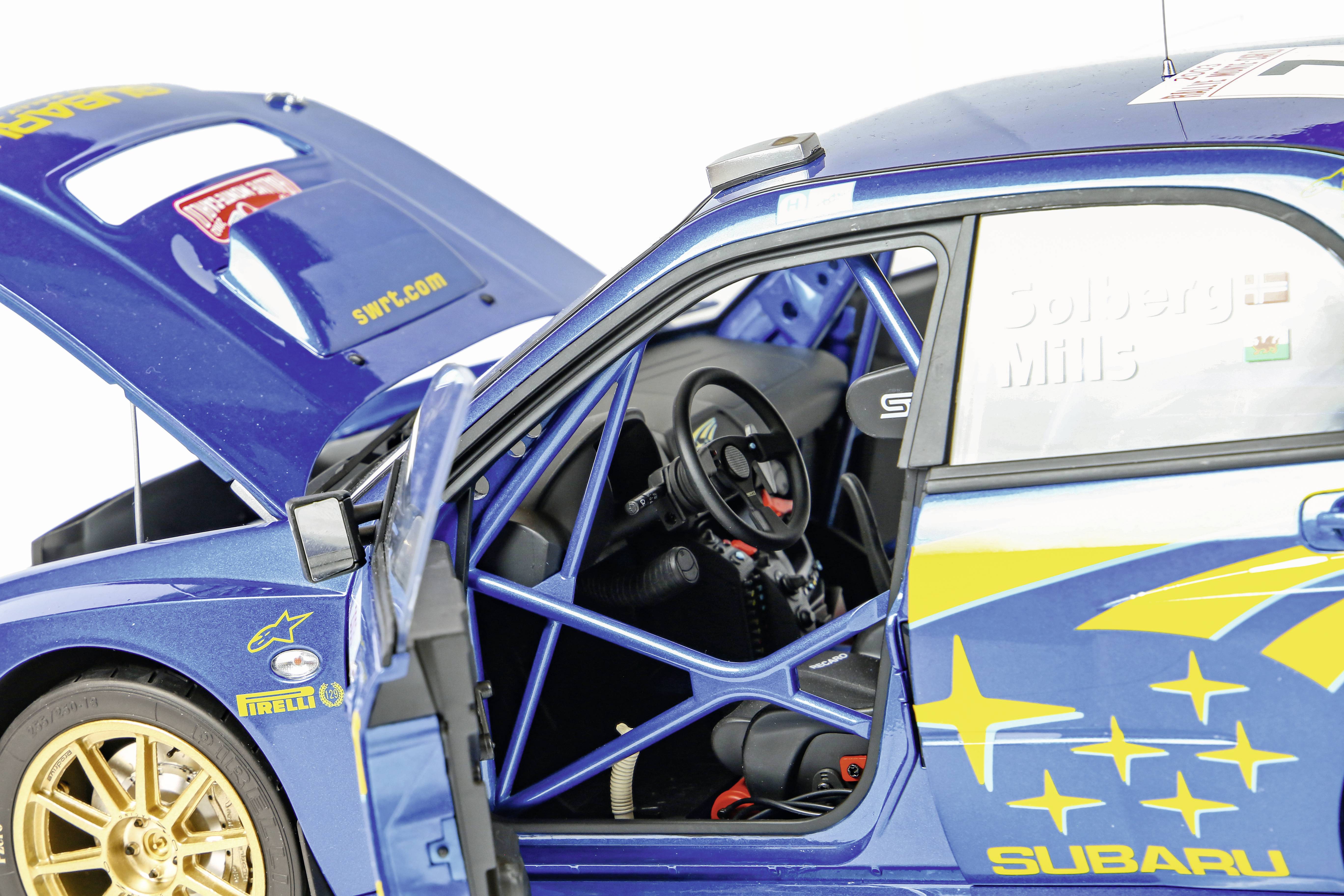 Een blauwe racewagen met een open bagageruimte en geopende bestuurdersdeur, toont een racecockpit en gele sterren op de carrosserie.