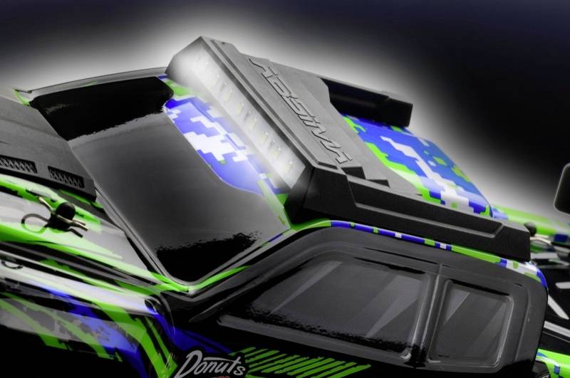 Een afstandsbediend auto met een blauw-groene camouflage en zwarte accenten. Op het dak staat 'AMASSADOR'.