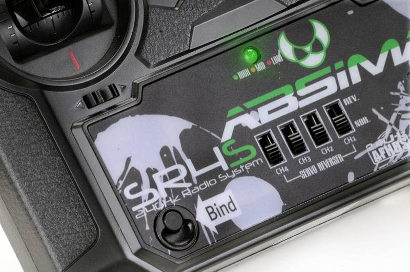 Een close-up van een afstandsbediening met de tekst '2.4 GHz Radio Systeem' en verschillende kanaalinstellingen, met een groen oplichtende LED.