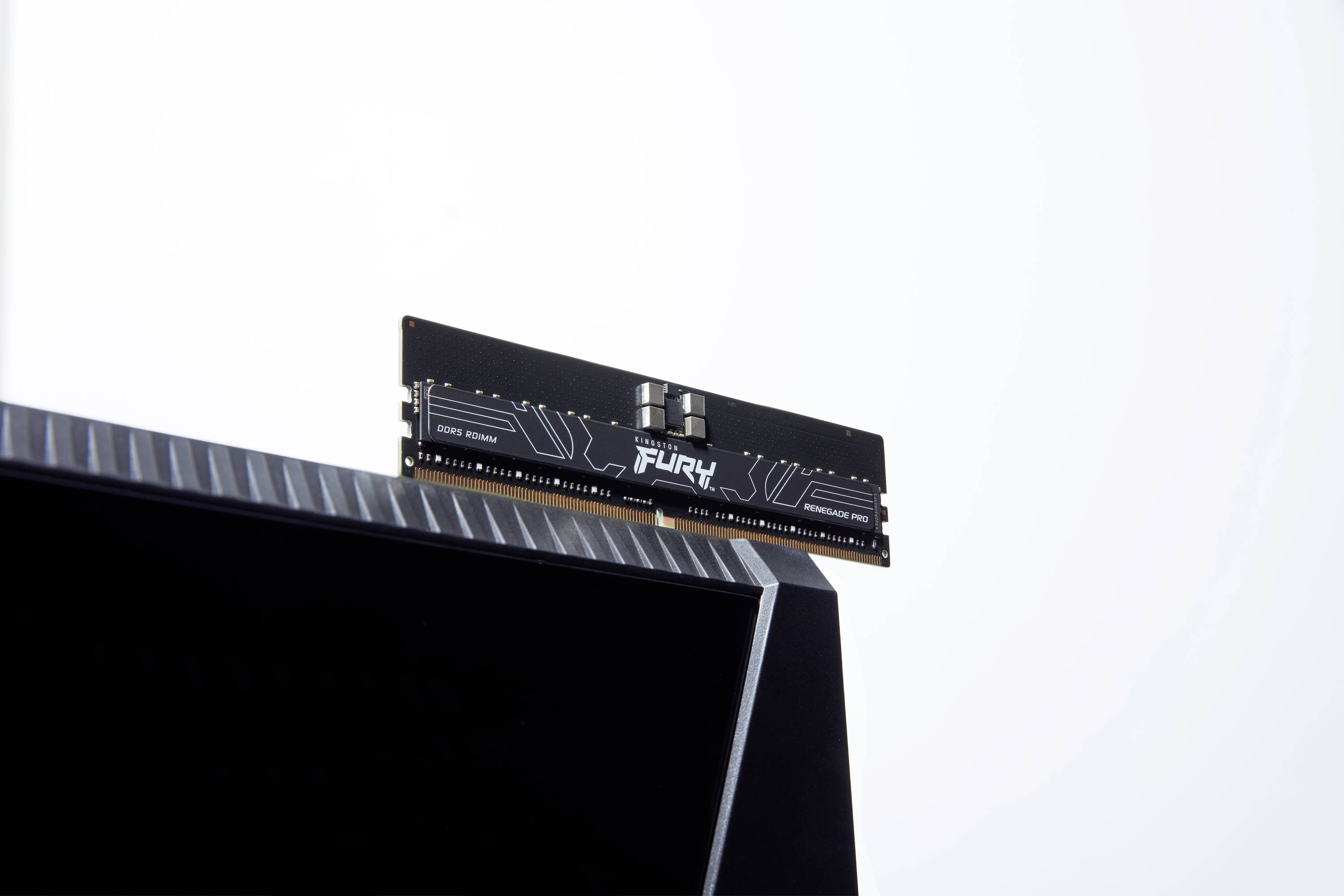 Een enkele RAM-module, verticaal geplaatst, met het opschrift 'FURY' op de module, rust op een zwarte computermonitor.