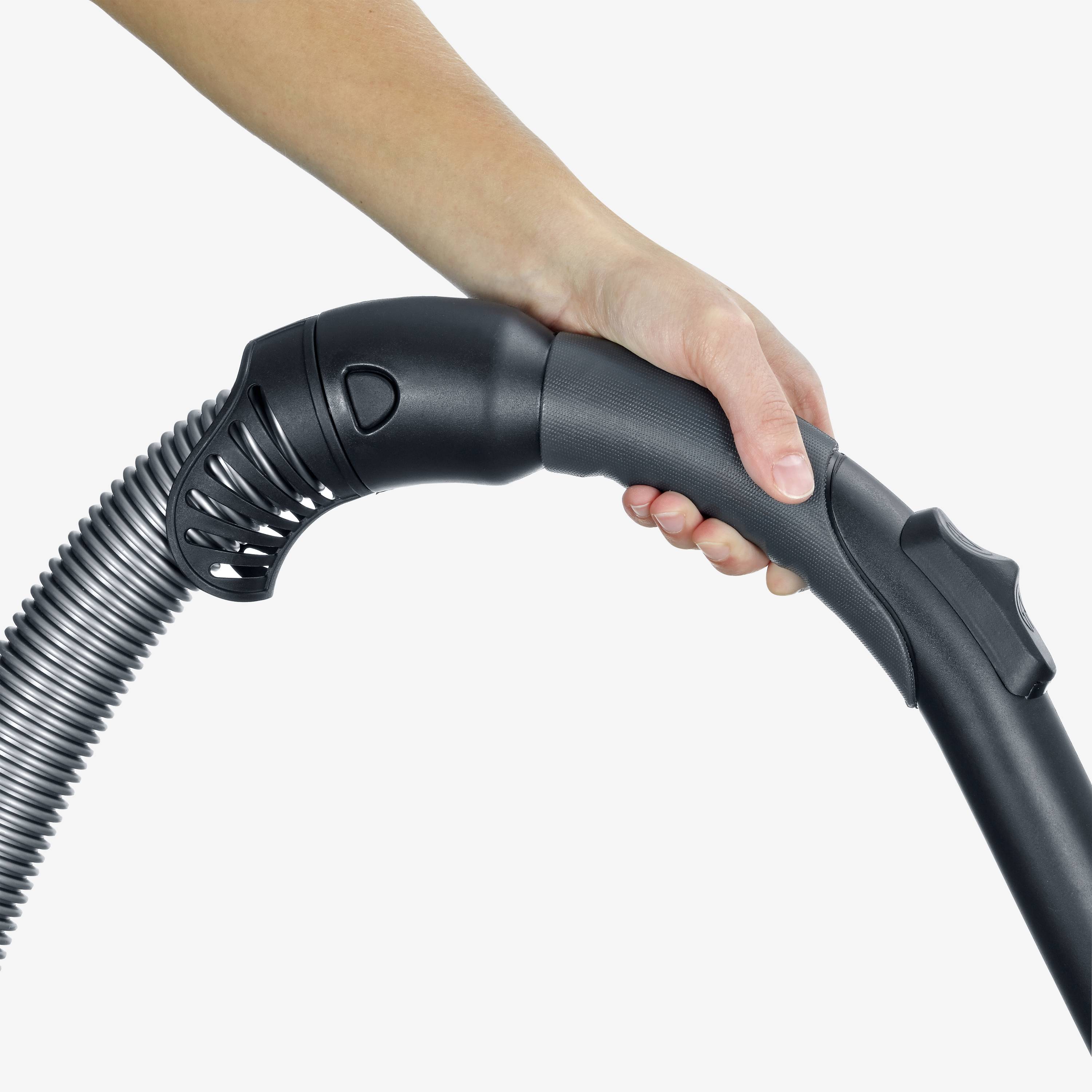 Een hand houdt de handgreep van een stofzuigerbuis vast met een geribberde flexibele slang die op de buis is aangesloten.