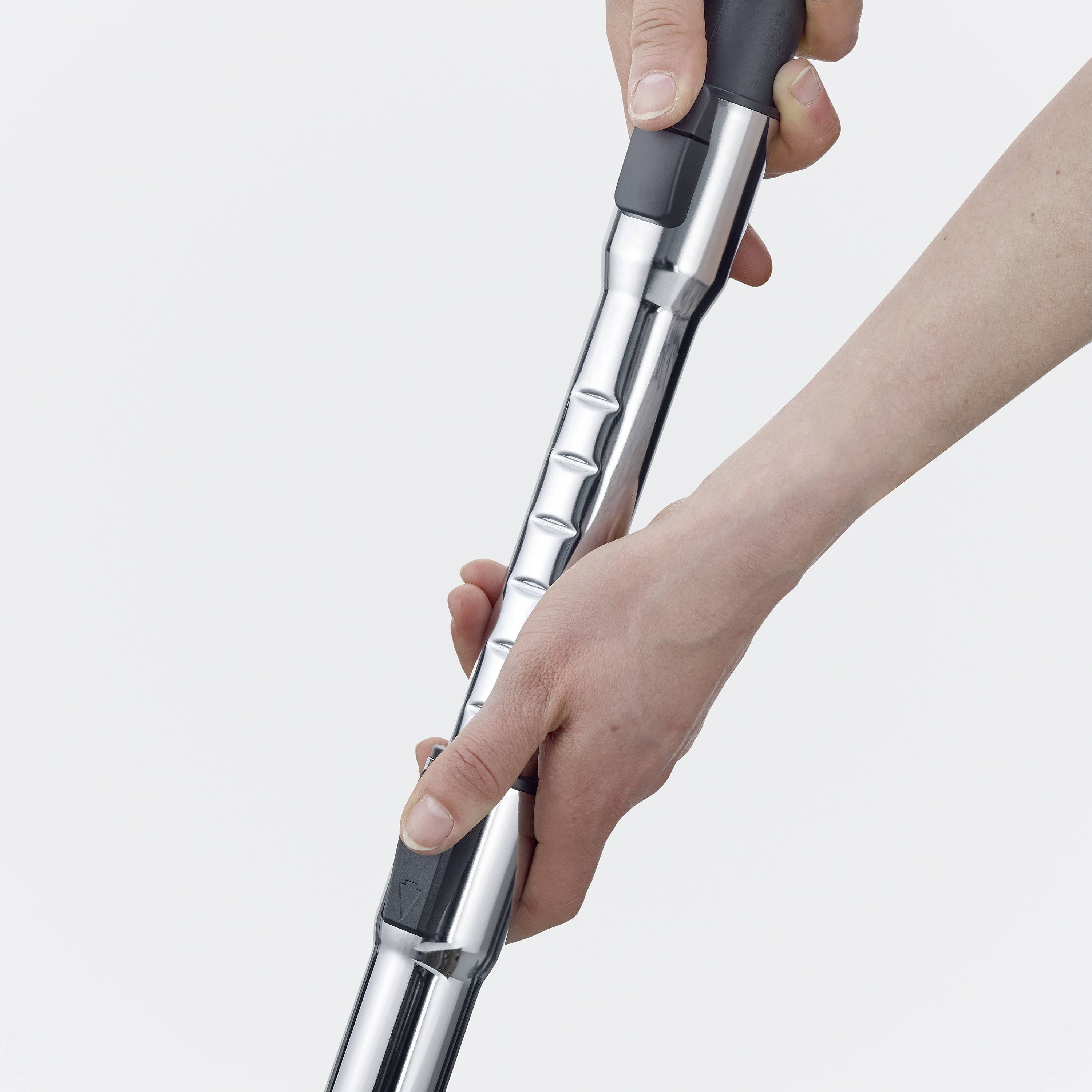 Een persoon houdt een stijlvolle stofzuiger met een glanzende metalen buis. De foto concentreert zich op de hand en het handvat.