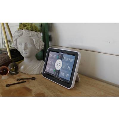 Een wit tablet toont verschillende meetwaarden, waaronder een centrale weergave van '3.2'. Het staat op een houten tafel naast een buste.