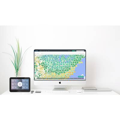 Een bureau met een Mac-computer toont een gekleurde weerskaart van Noord-Amerika. Ernaast staat een tablet met weergegevens.