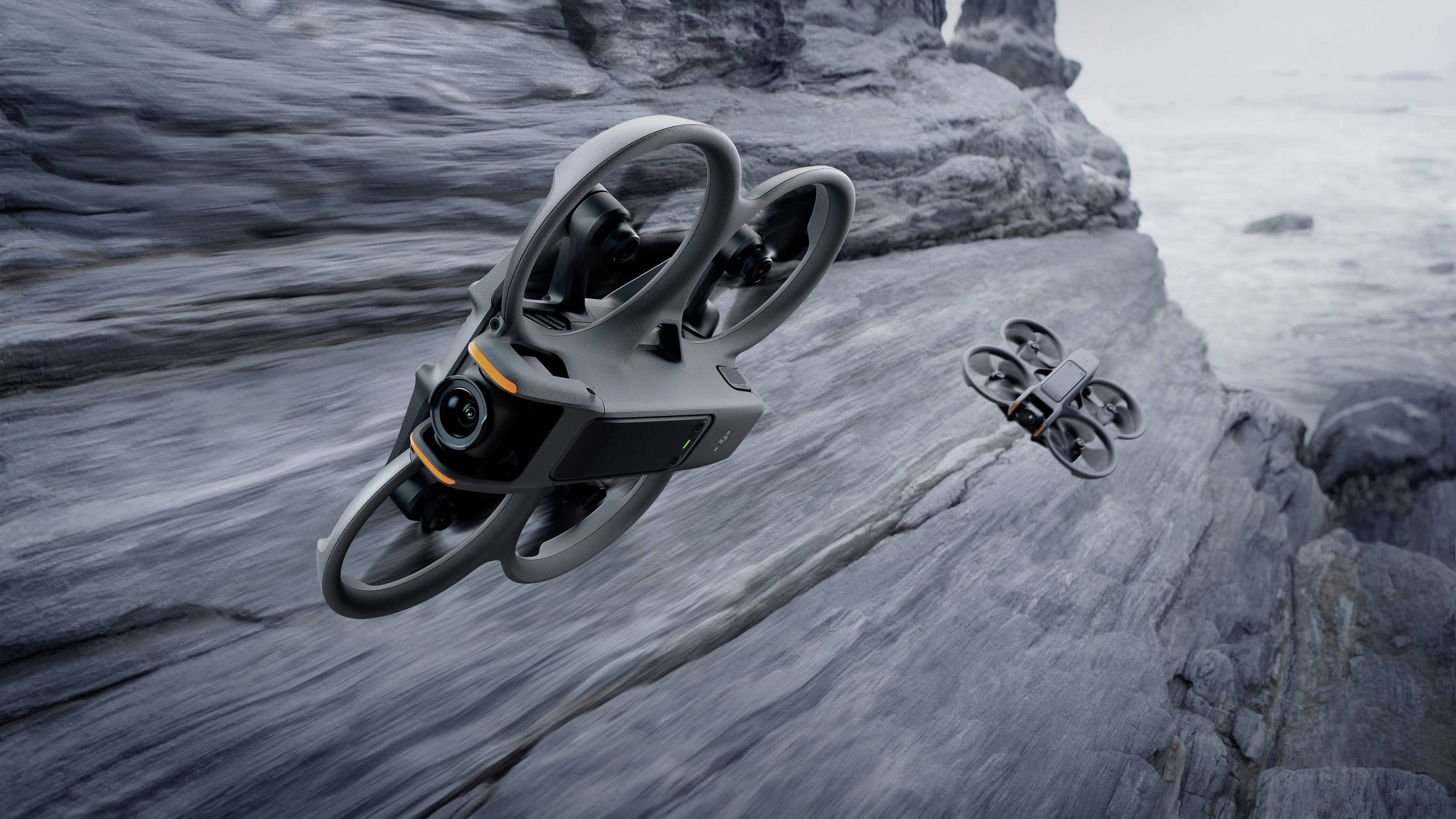 Twee drones vliegen over een rotsachtig kustlandschap. De omgeving ziet er stormachtig en onherbergzaam uit.