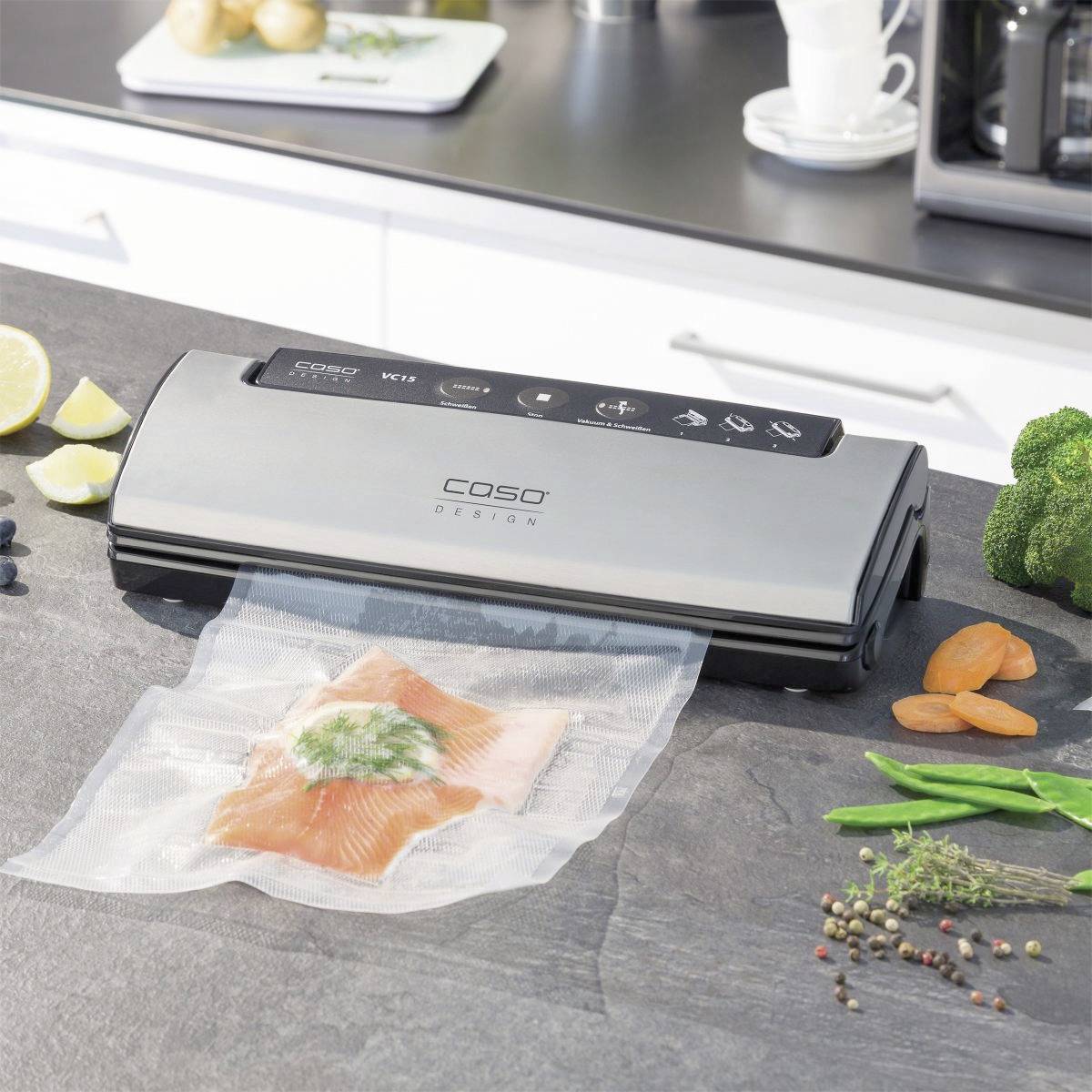 Vacuümmachine op een aanrecht verzegelt een stuk zalm in plastic. Omringd door groenten en kruiden.