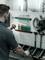 Een man rangschikt gereedschappen aan een geperforeerde wand, waaronder schroevendraaiers, moersleutels en een elektrisch gereedschap, in een werkplaats.
