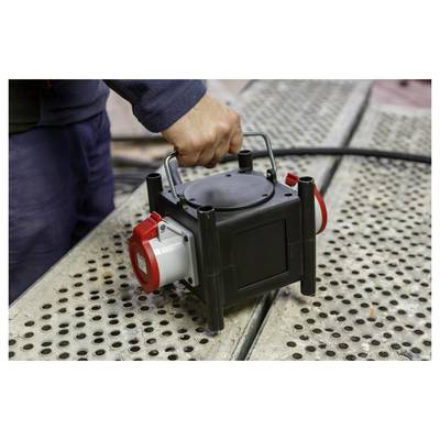 Hand die een draagbare elektrische pomp of generator op een geperforeerd metalen oppervlak buitenshuis vasthoudt.
