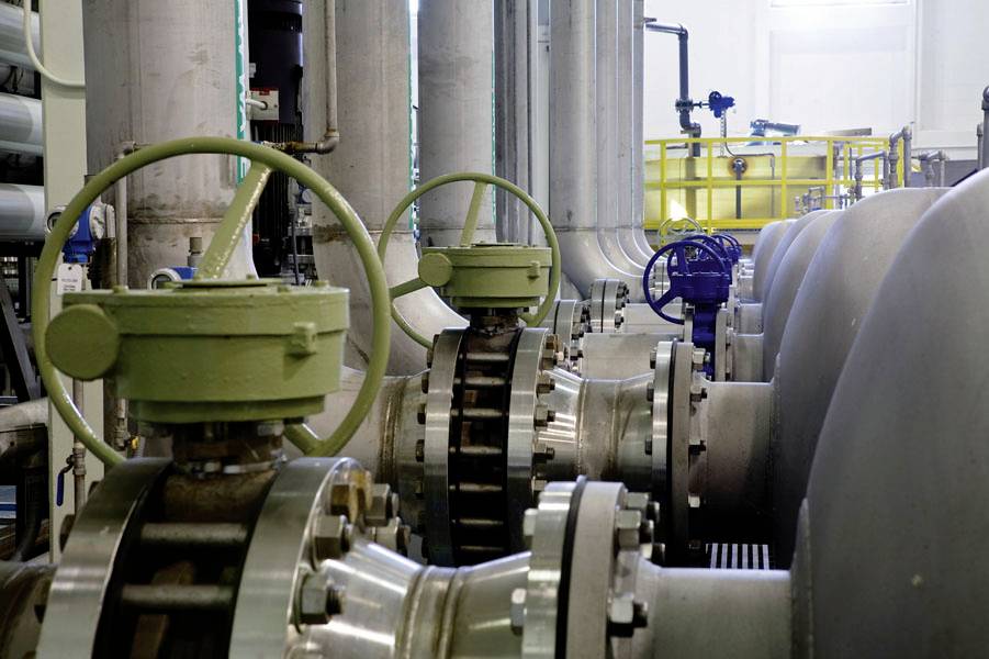 Grote industriële kleppen en buizen in een moderne machinekamer. De installatie lijkt ontworpen te zijn voor een industrieel proces.