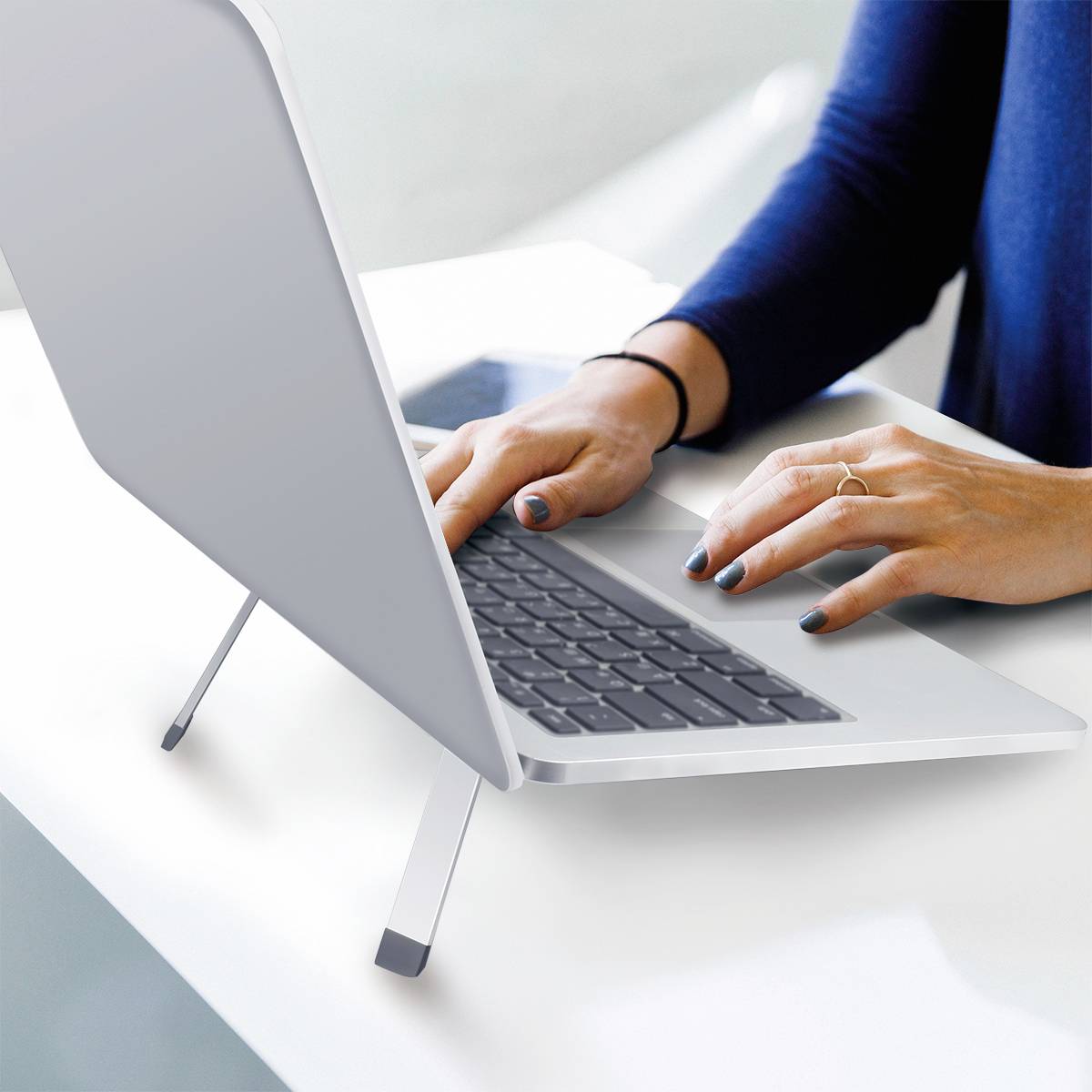 Een persoon werkt op een laptop en typt op het toetsenbord. Op de achtergrond is een lichte kamer zichtbaar.