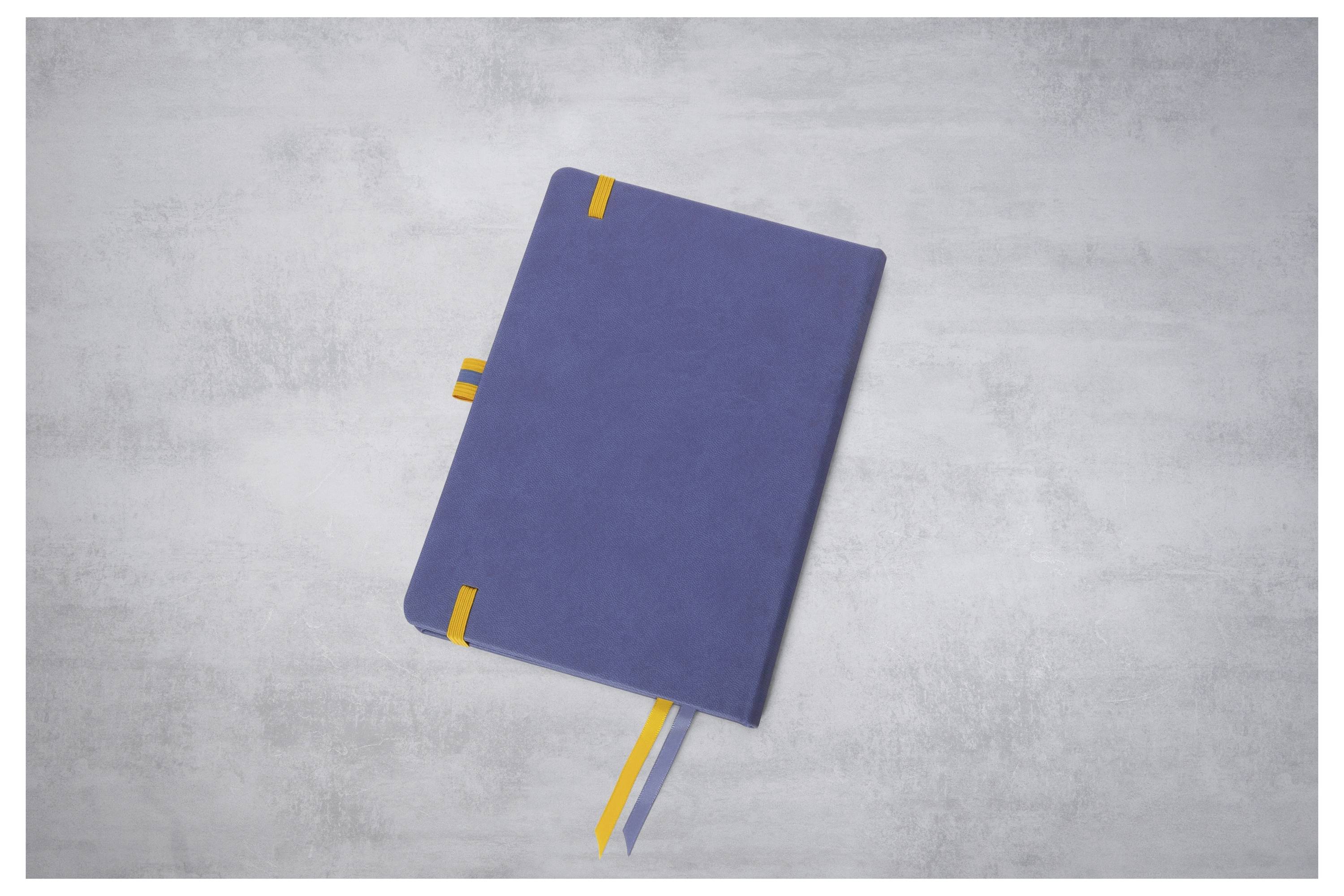 Blauw notitieboekje met geel lintboekenlegger op een lichtgrijs oppervlak, van bovenaf bekeken.