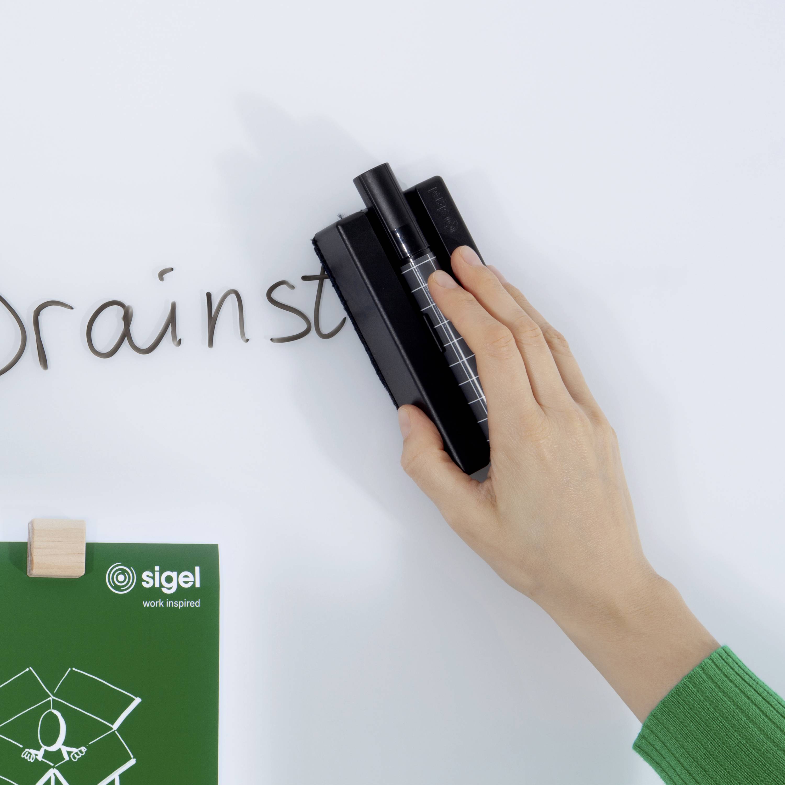 'Brainstormen' wordt op een whiteboard geschreven terwijl een hand een pen vasthoudt; op de achtergrond een logo met de tekst 'Sigel'.