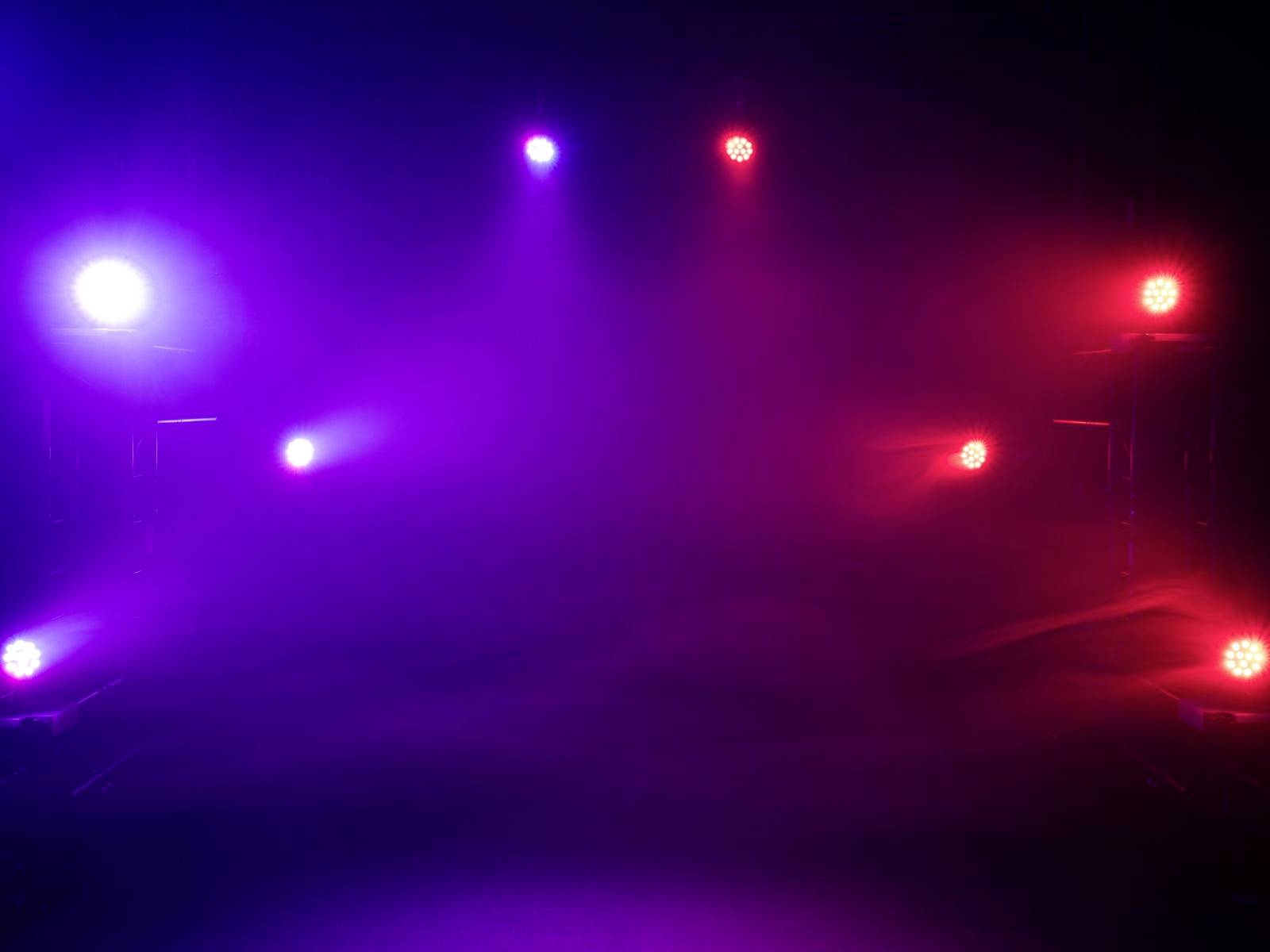 Podium verlicht met paarse en rode schijnwerpers, in een donkere omgeving. Geen andere objecten of personen zichtbaar.