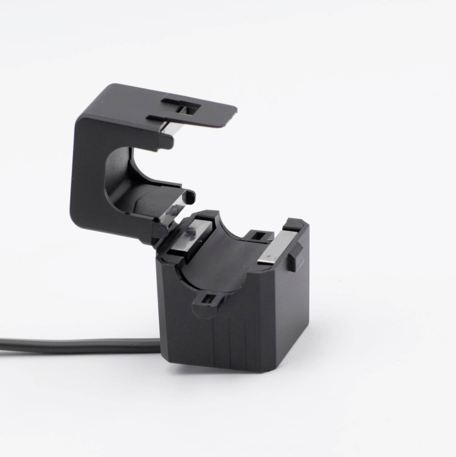 Een zwarte, vierkante elektrische aansluitblok met kabelaansluiting staat open en toont de binnenkant van de klem.