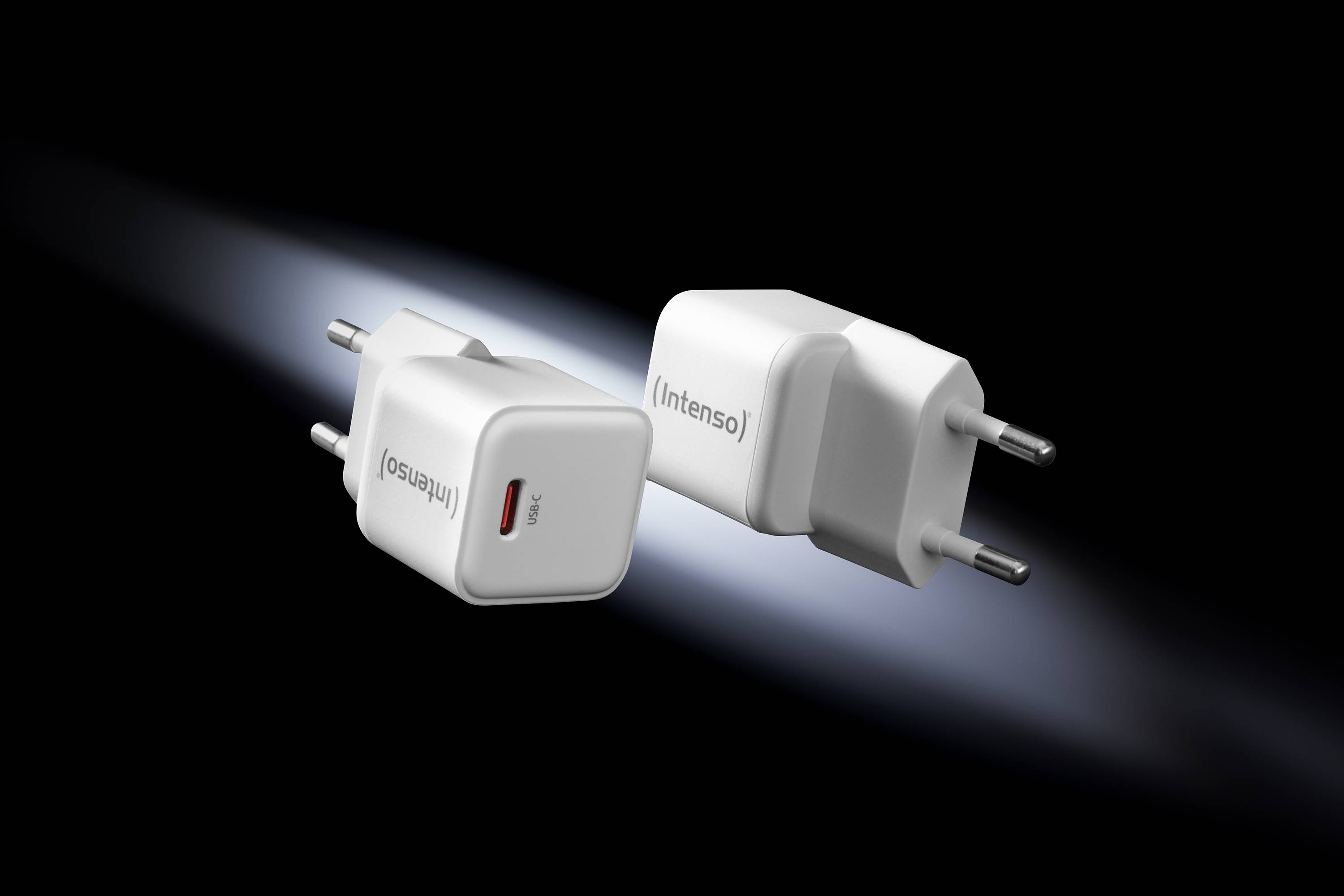 Twee witte USB-opladers met het opschrift 'Intenso' zweven voor een zwarte achtergrond, zijdelings verlicht.
