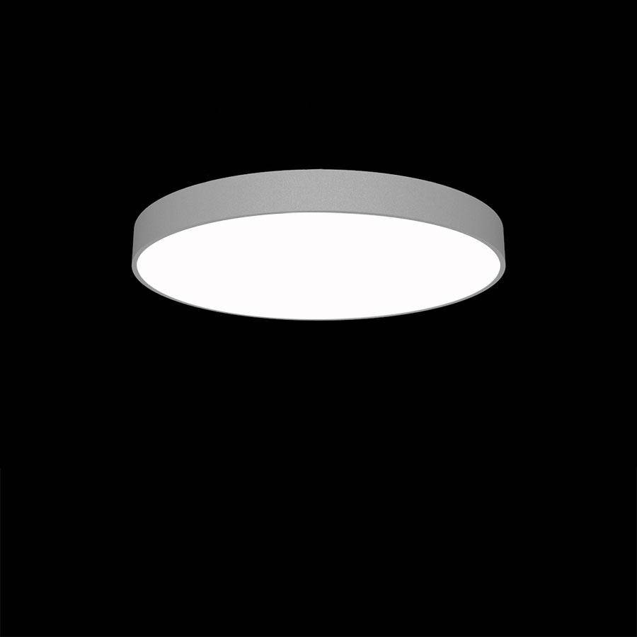 'Ronde, moderne plafondlamp met zacht wit licht, zweeft in donkere ruimte.'