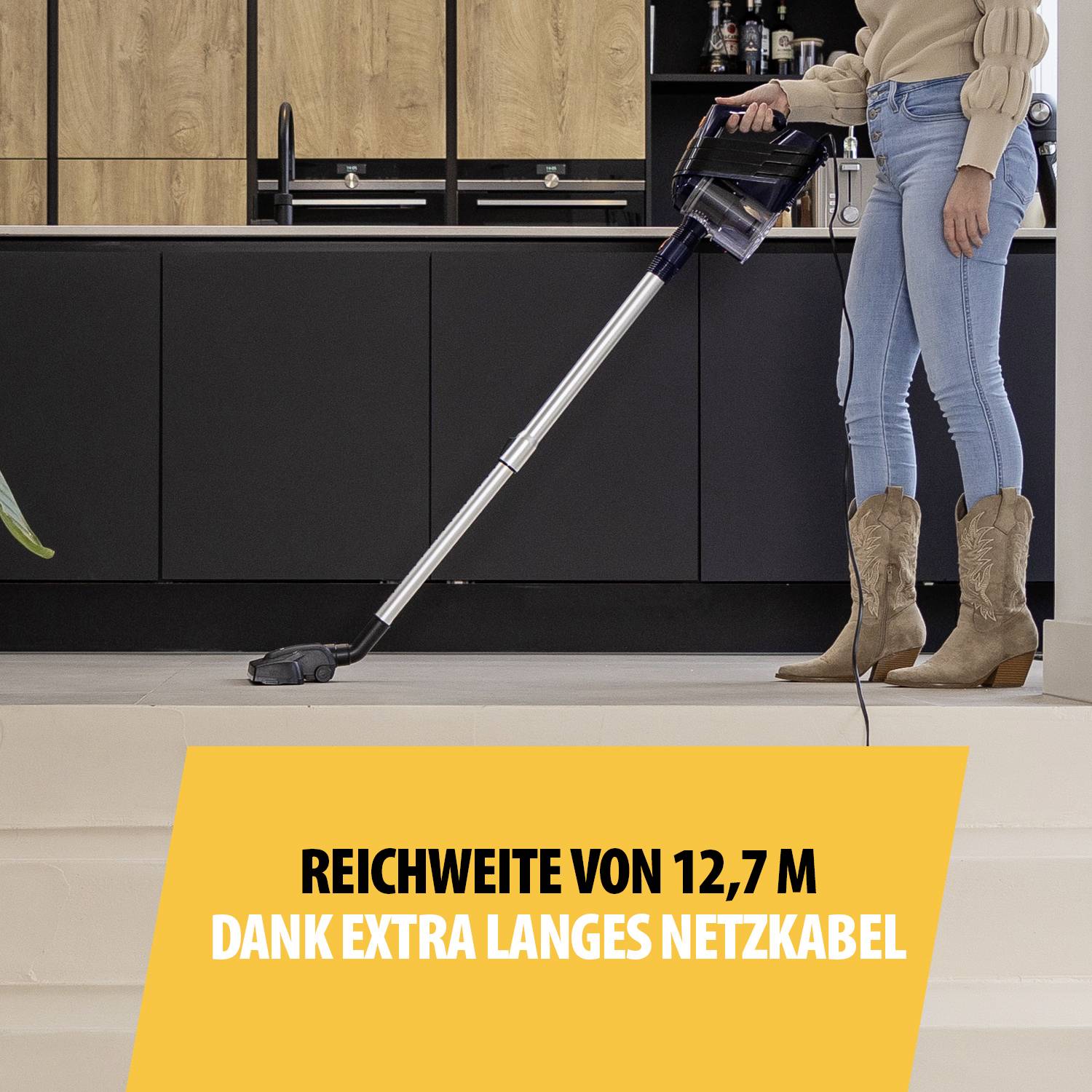 Vrouw zuigt vloer met een stofzuiger; tekst benadrukt 'Bereik van 12,7 m dankzij extra lang netsnoer'.