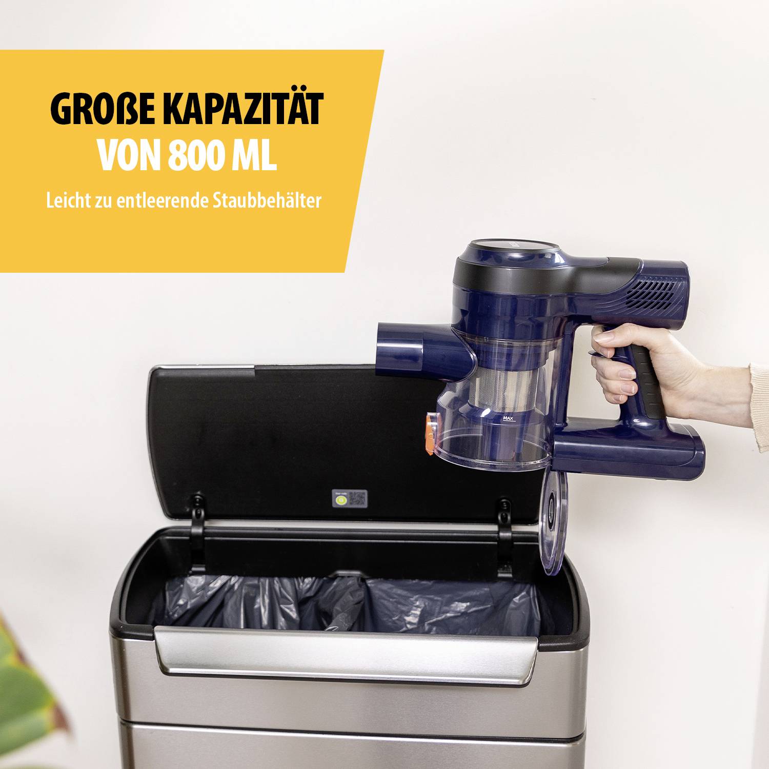 Draadloze stofzuiger die wordt leeggemaakt boven een open vuilnisemmer. Tekst in het Geel: 'Grote capaciteit van 800 ml'.