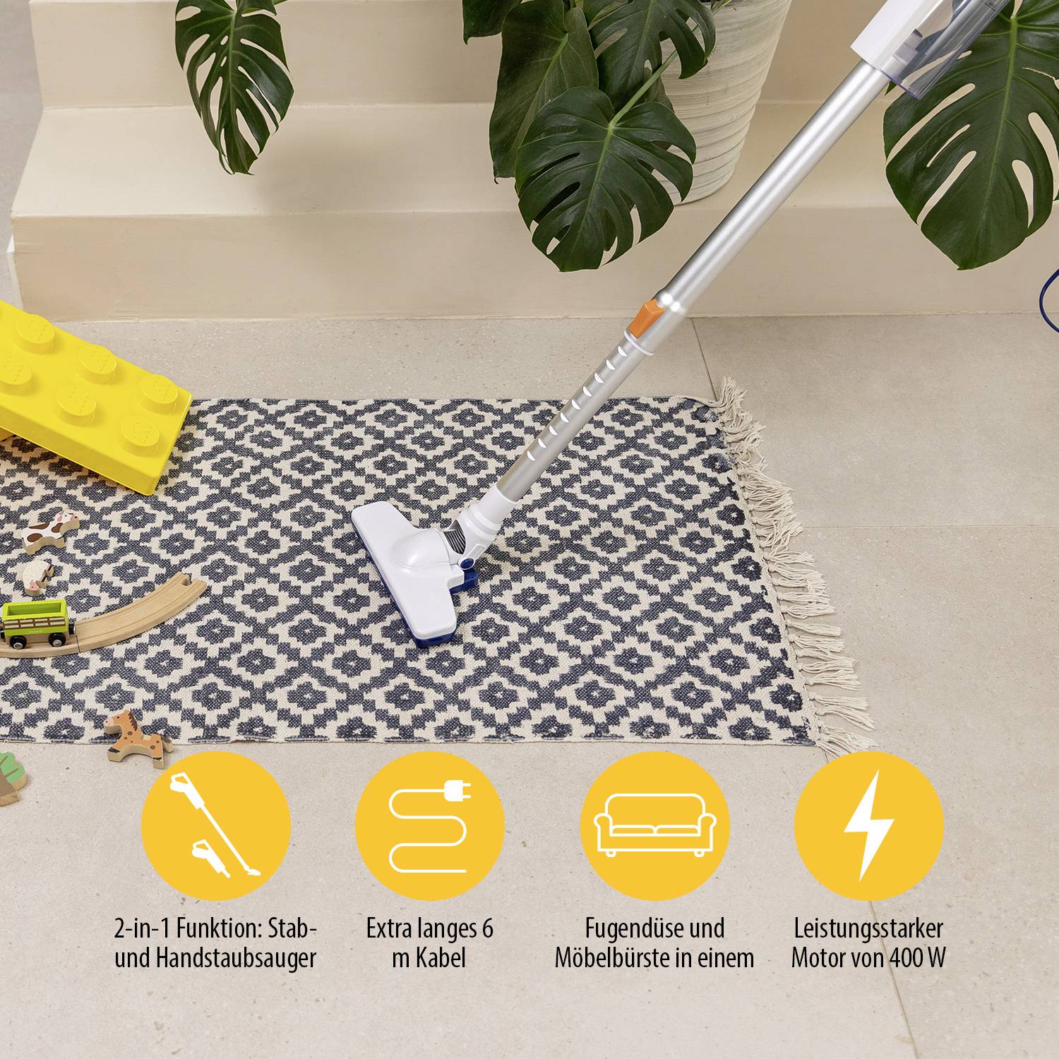 Een witte steelstofzuiger op een blauw-wit tapijt, omringd door speelgoed; reclame voor 2-in-1 functies en 6 m kabel.