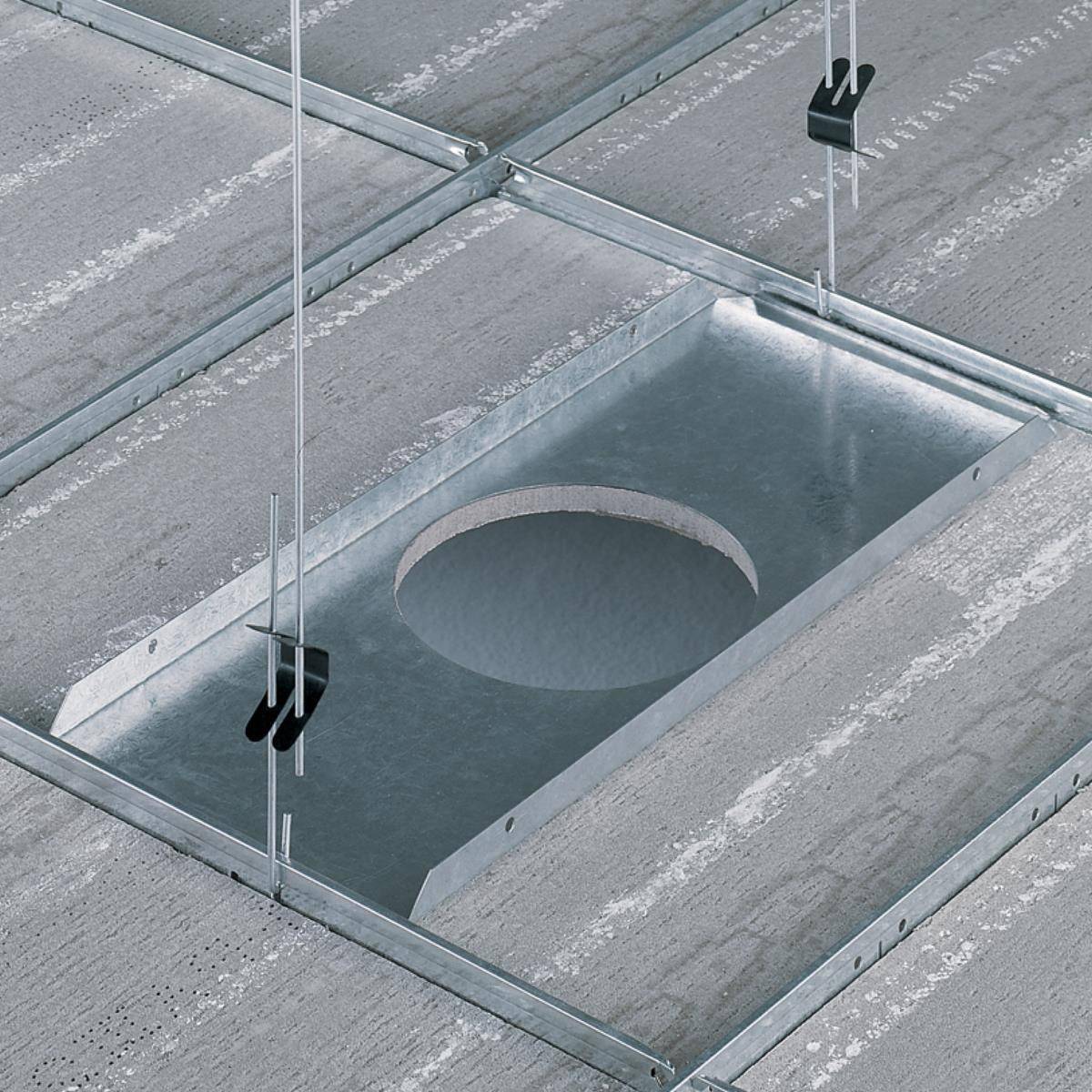 Metalen plaat met ronde uitsparing, hangt aan draadkabels onder een betonnen plafond, onderdeel van een installatiesysteem.