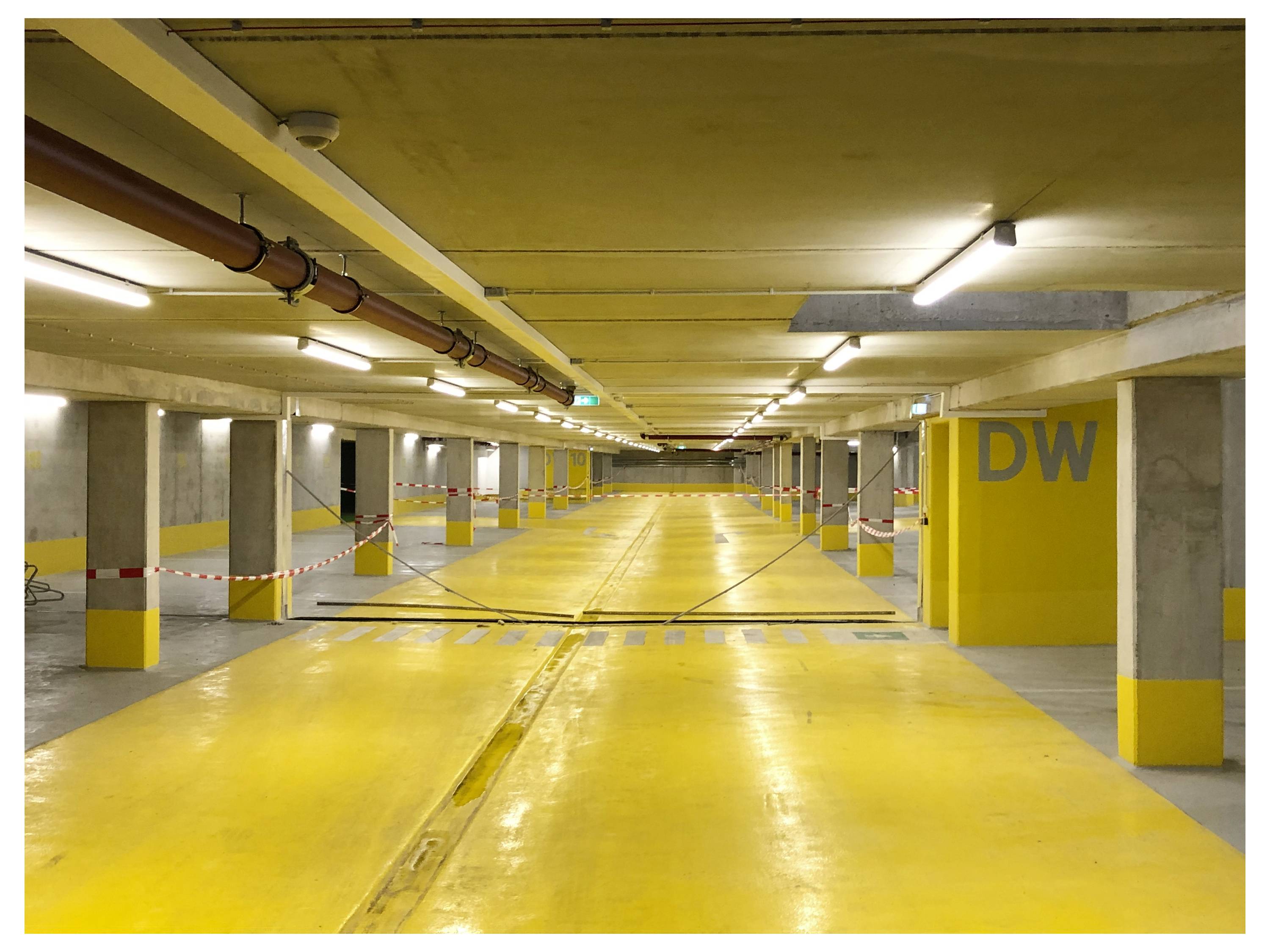 Gang in een gebouw met verschillende gesloten deuren, elk genummerd, met '522' scherp in beeld. Het plafond heeft zichtbare nutsbuizen en verlichting.
