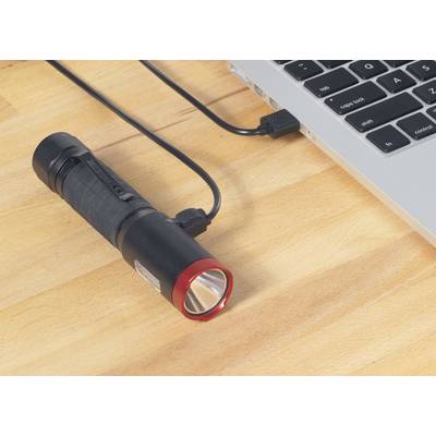 Zaklamp met rode rand wordt opgeladen via een USB-kabel aangesloten op een laptop.