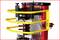 Een rode machine met gele beschermbeugels die een schroefveer comprimeert. Hij wordt blijkbaar gebruikt voor veerwerk.