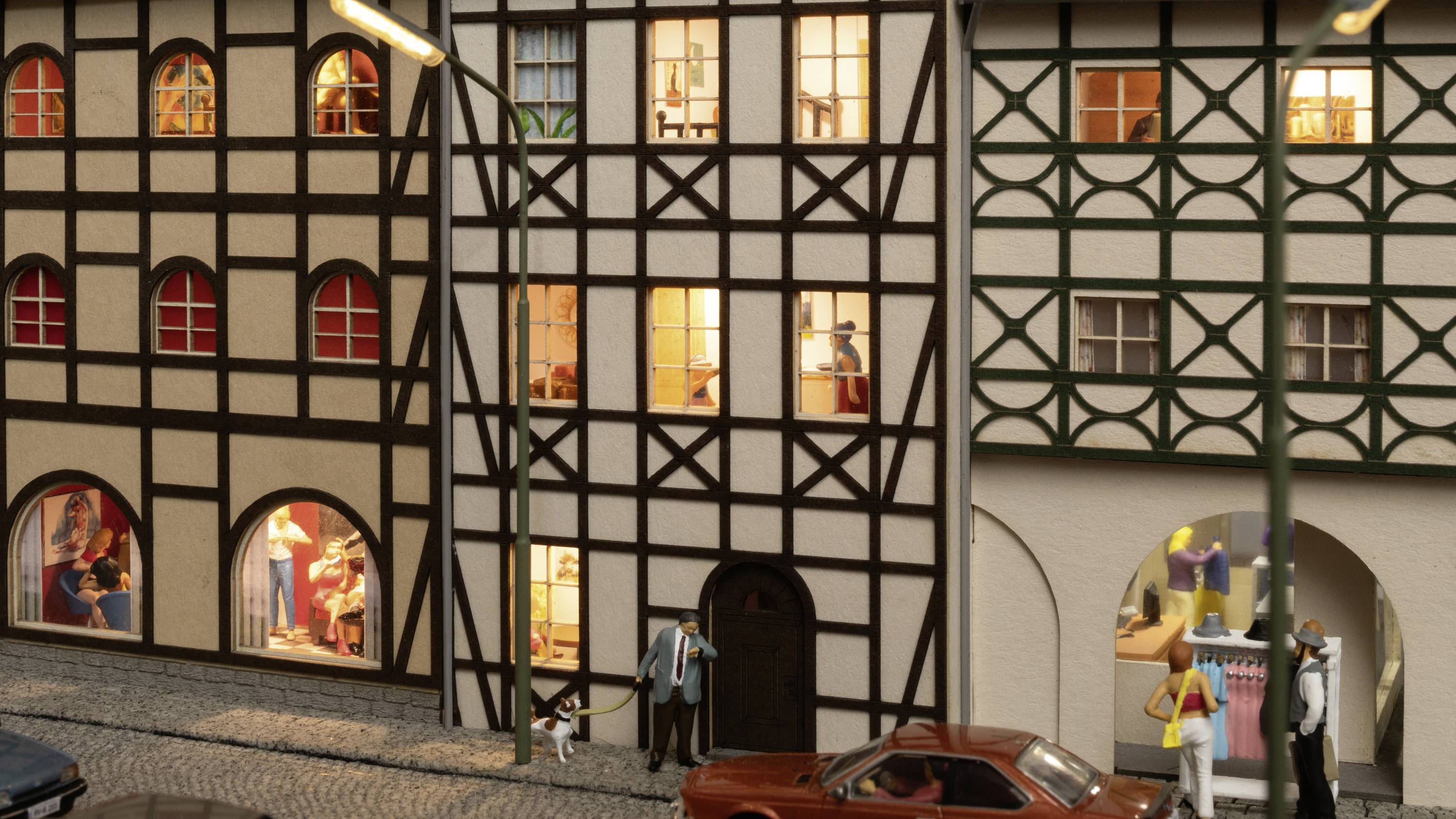 Model van een straatje in de oude binnenstad met vakwerkhuizen, verlichte ramen en kleine figuurtjes. Auto's zijn geparkeerd langs de geplaveide straat.