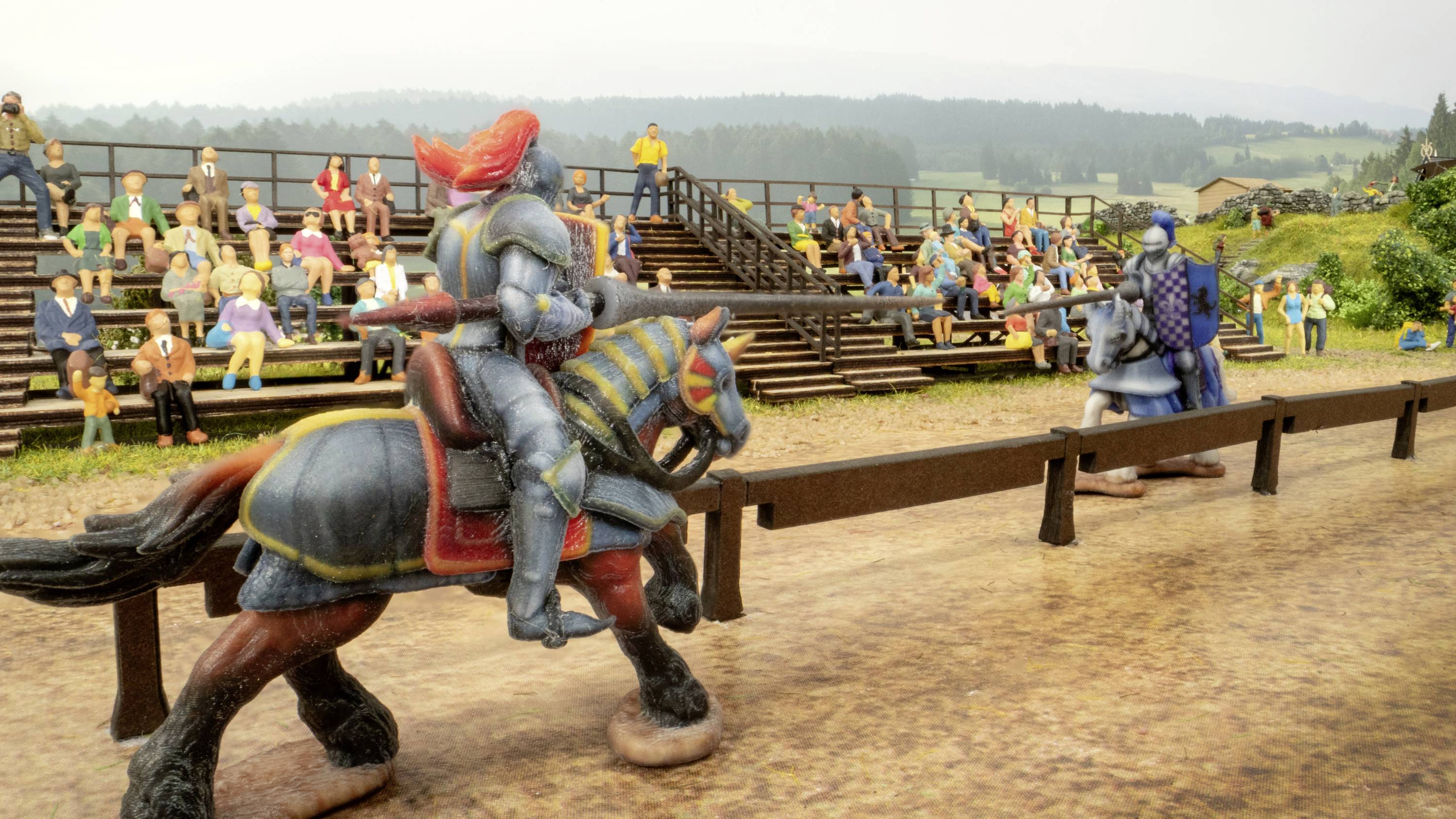 Twee ridders in harnassen te paard tijdens een toernooi. Toeschouwers zitten op tribunes op de achtergrond. Gebouwen en bomen in de verte.