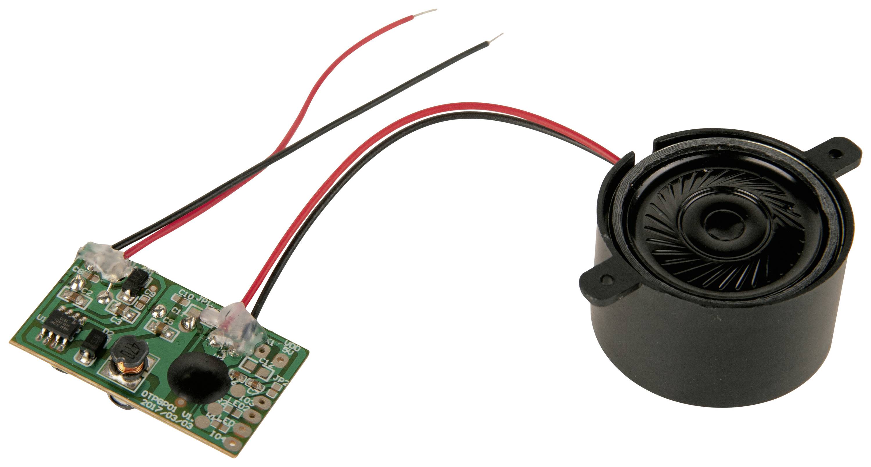 Een kleine groene printplaat met een aangesloten ronde zwarte luidspreker. Twee draden verbinden de componenten.