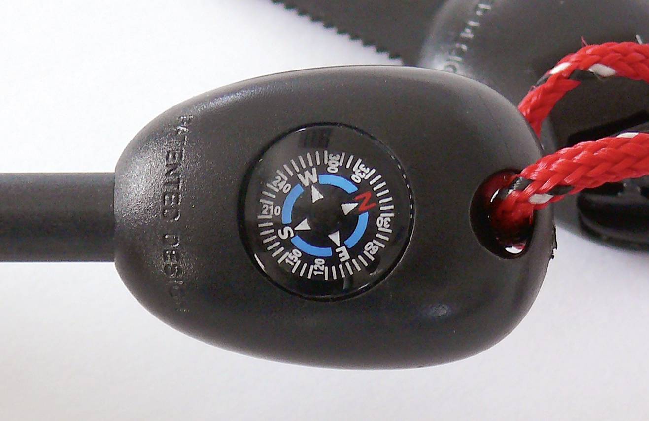 Een zwarte kompas met rode touwen wijst de windrichtingen aan. De achtergrond is wazig en wit.