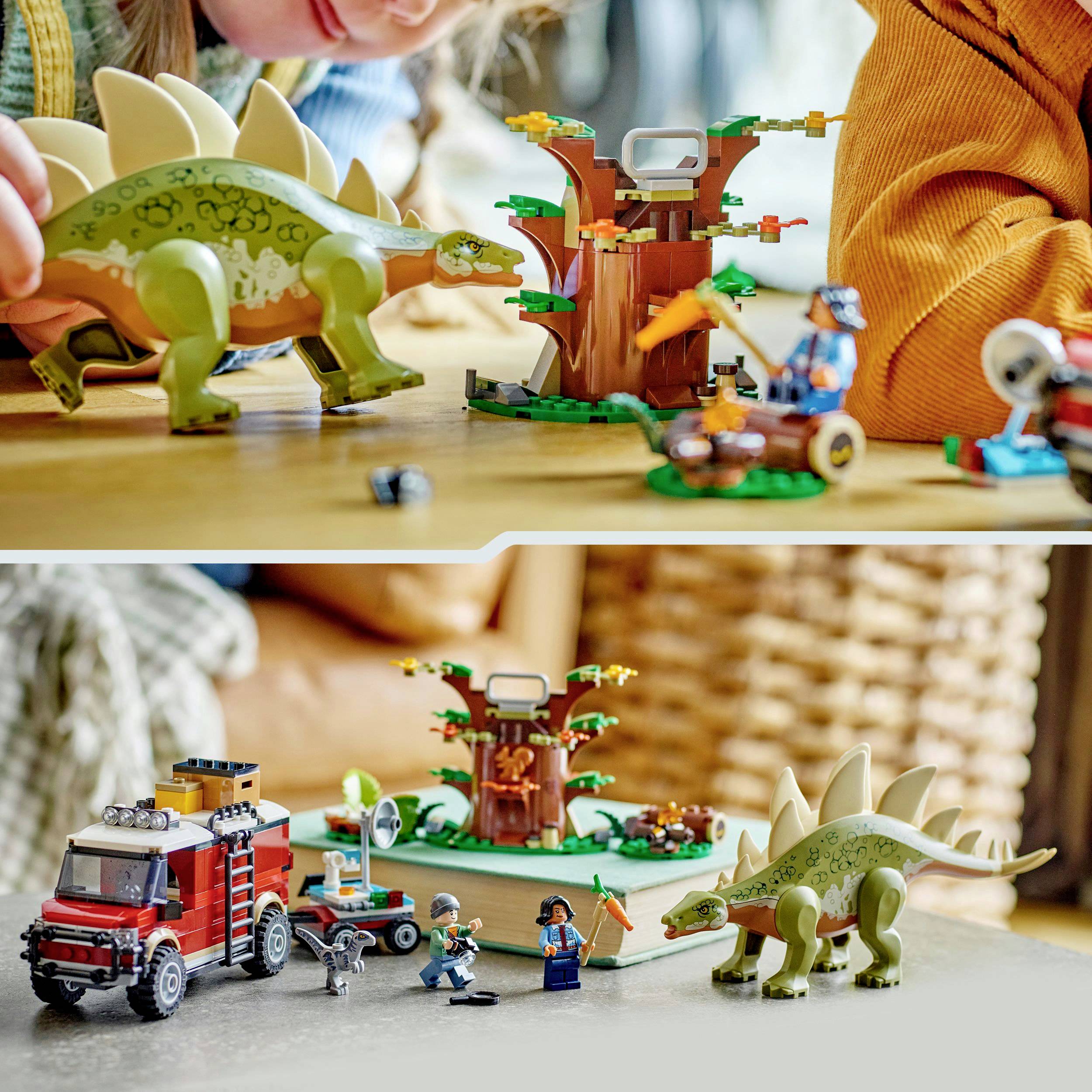 Kinderen spelen met een dinosaurus speelgoedset. Bevat een groene dinosaurus, boomstructuur en een brandweerwagen op een tafel.
